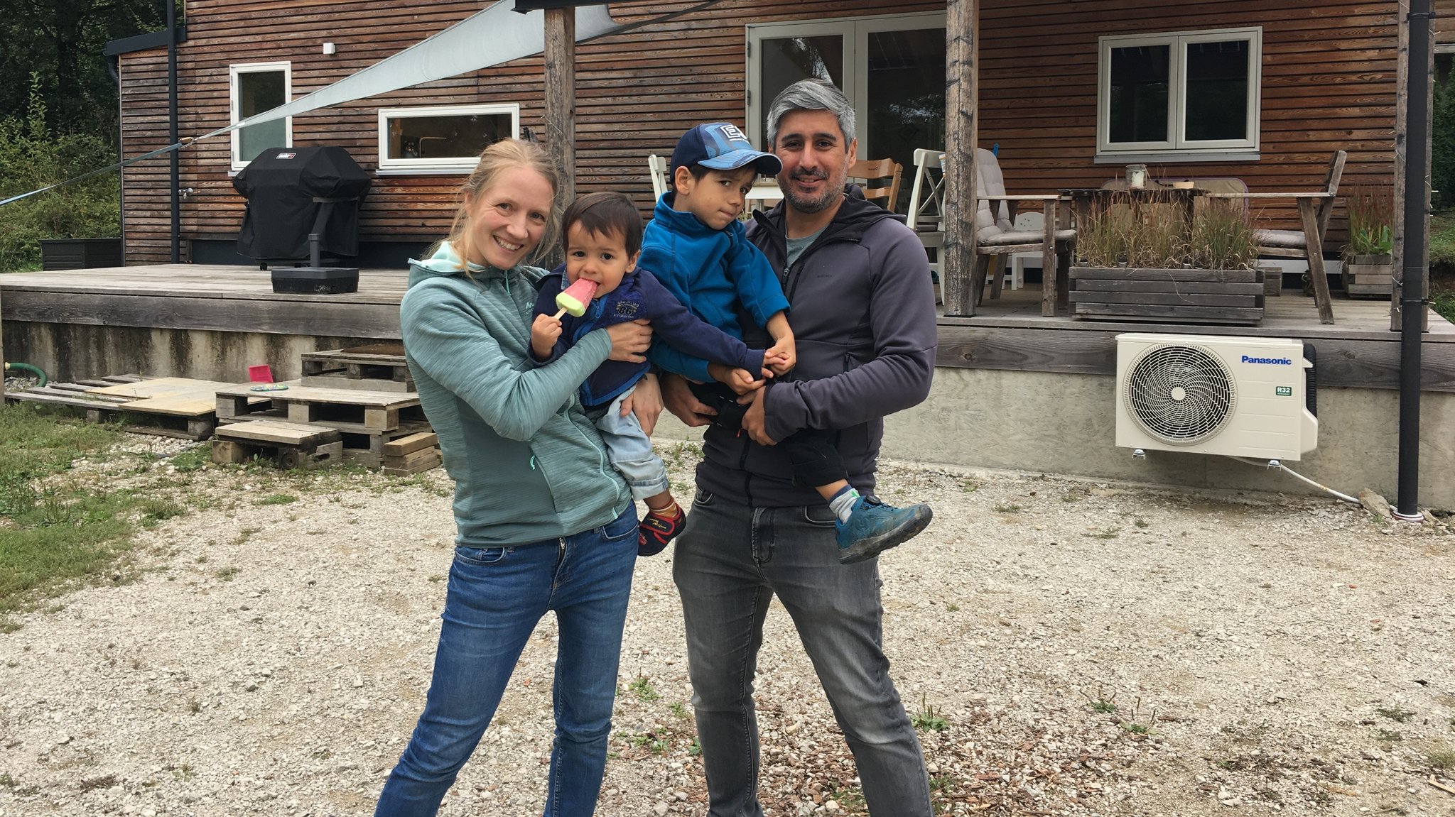 Zwei Erwachsene und zwei Kinder vor einem kleinen Haus.