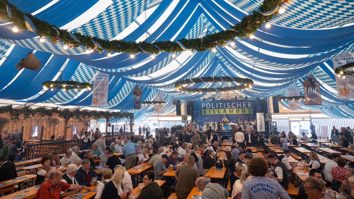 Besucher sitzen vor Beginn des Politischen Frühschoppens 2022 auf dem Gillamoos-Jahrmarkt im Bierzelt.