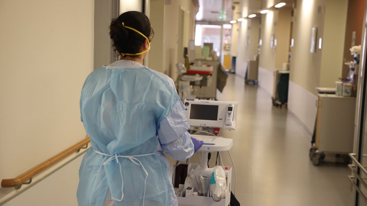 Eine Krankenschwester läuft mit medizinischem Gerät auf einer Corona "Normalstation".