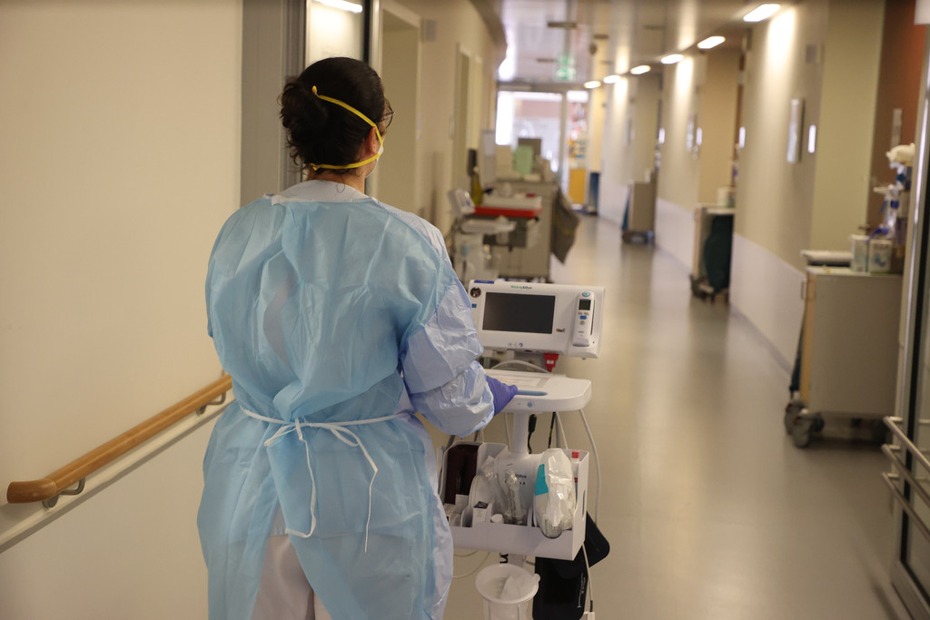 Eine Krankenschwester läuft mit medizinischem Gerät auf einer Corona "Normalstation".