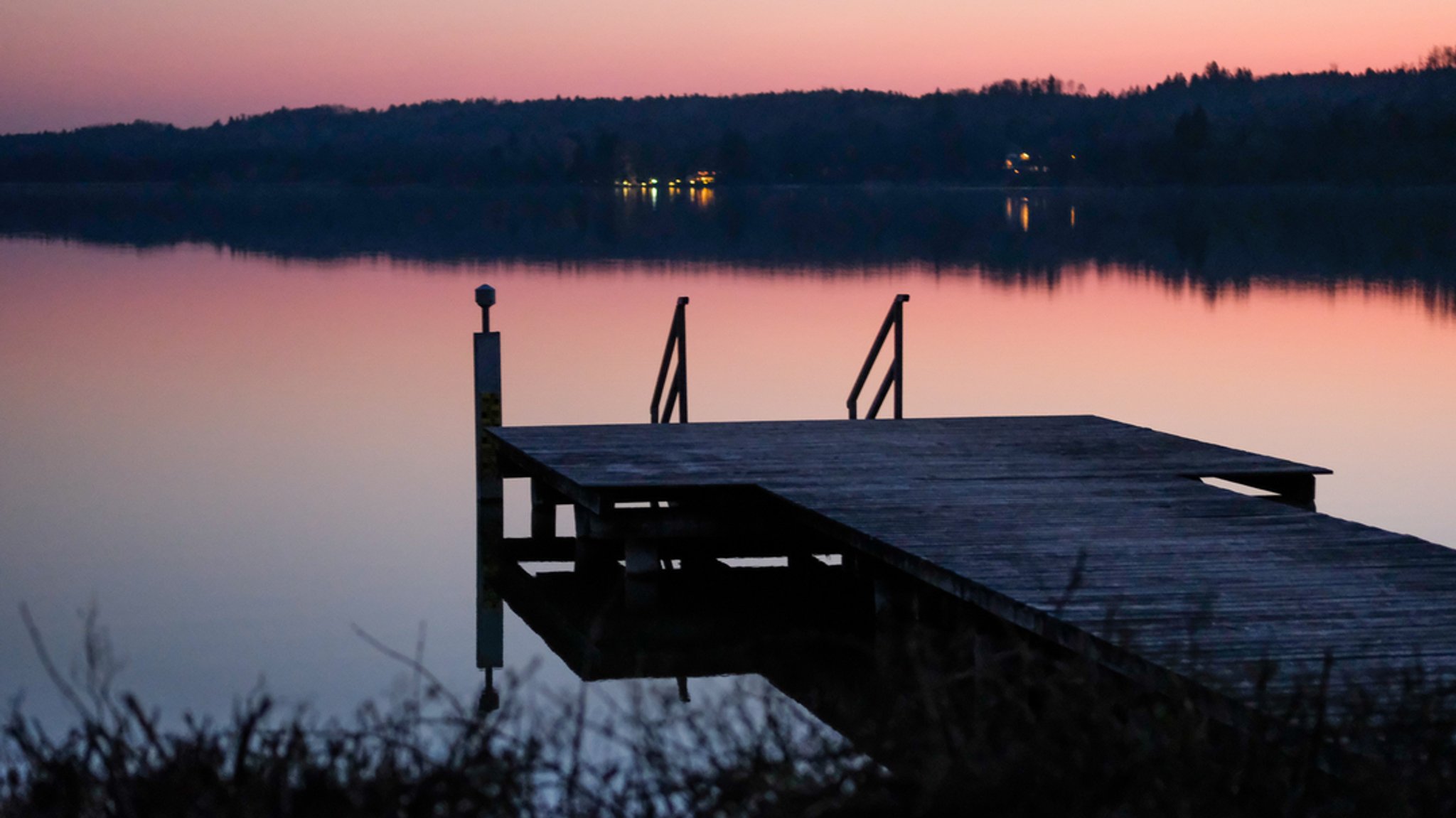 Der Ammersee mit einem Steg im Vordergrund während eines Sonnenuntergangs.