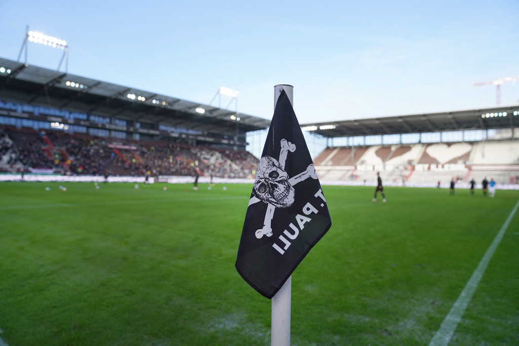 Eine Eckfahne mit Totenkopf-Logo seht auf einem Fußballplatz.