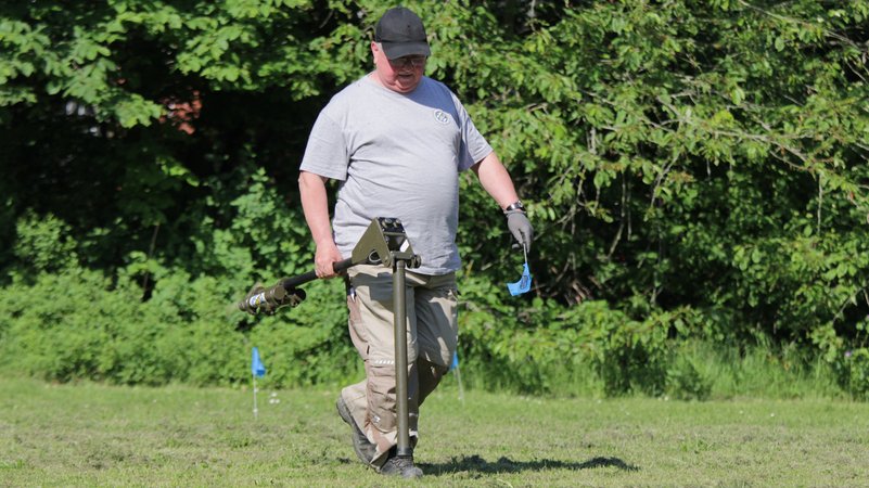 Ein Mann läuft mit einer Sonde über eine Wiese. | Bild: BR24/Antje Schönherr Ein Mann läuft mit einer Sonde über eine Wiese.