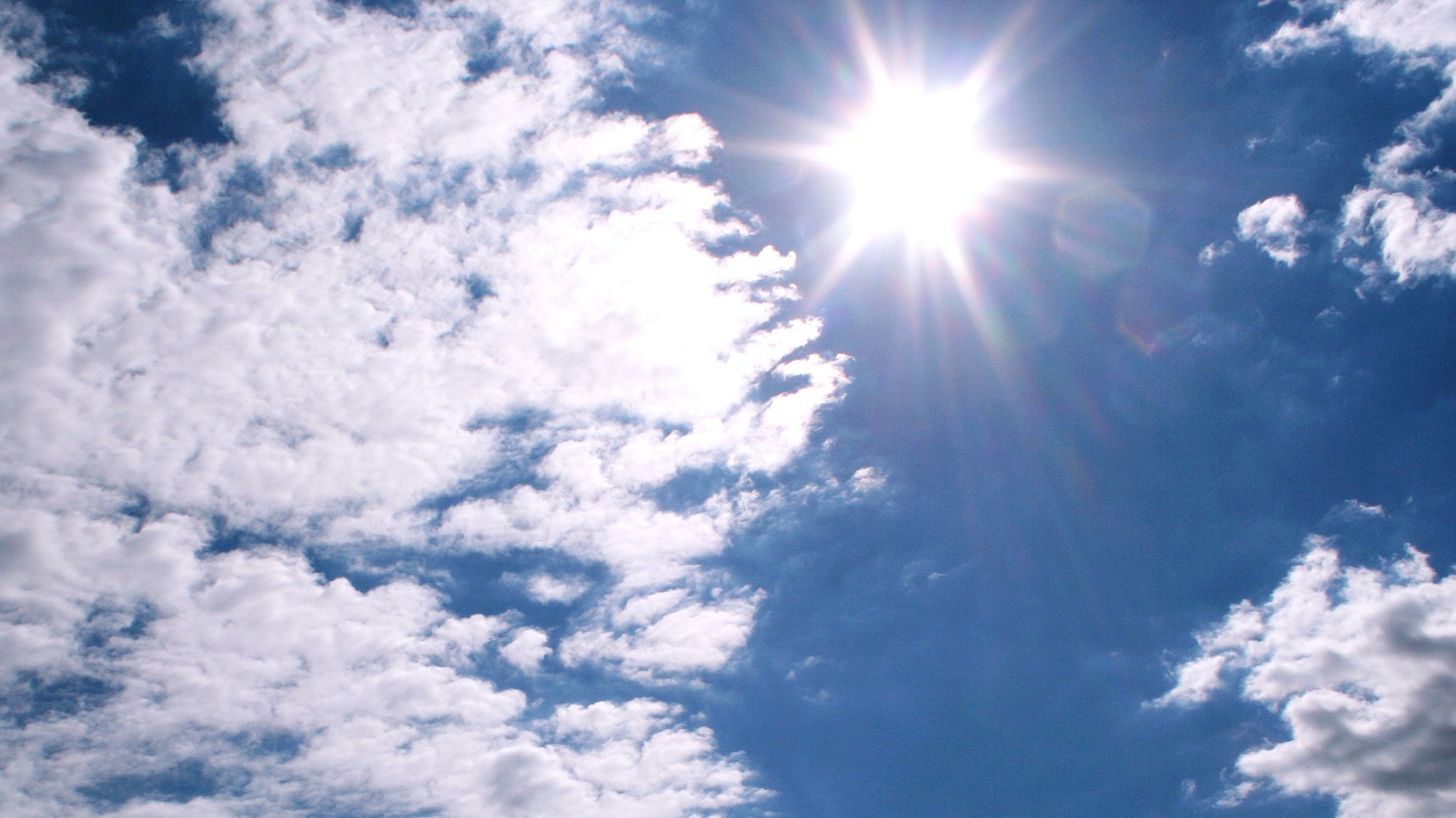 Sonne und Wolken am blauen Himmel