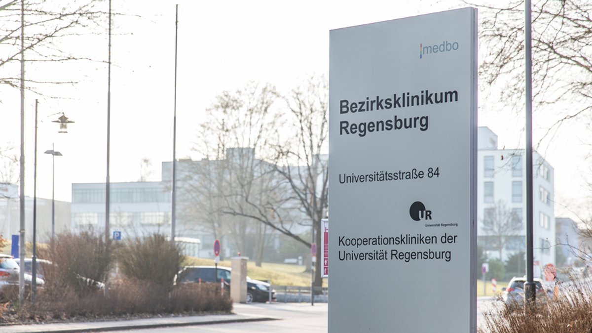 Ein Schild mit der Aufschrift Bezirksklinikum Regensburg steht vor mehreren Gebäuden.