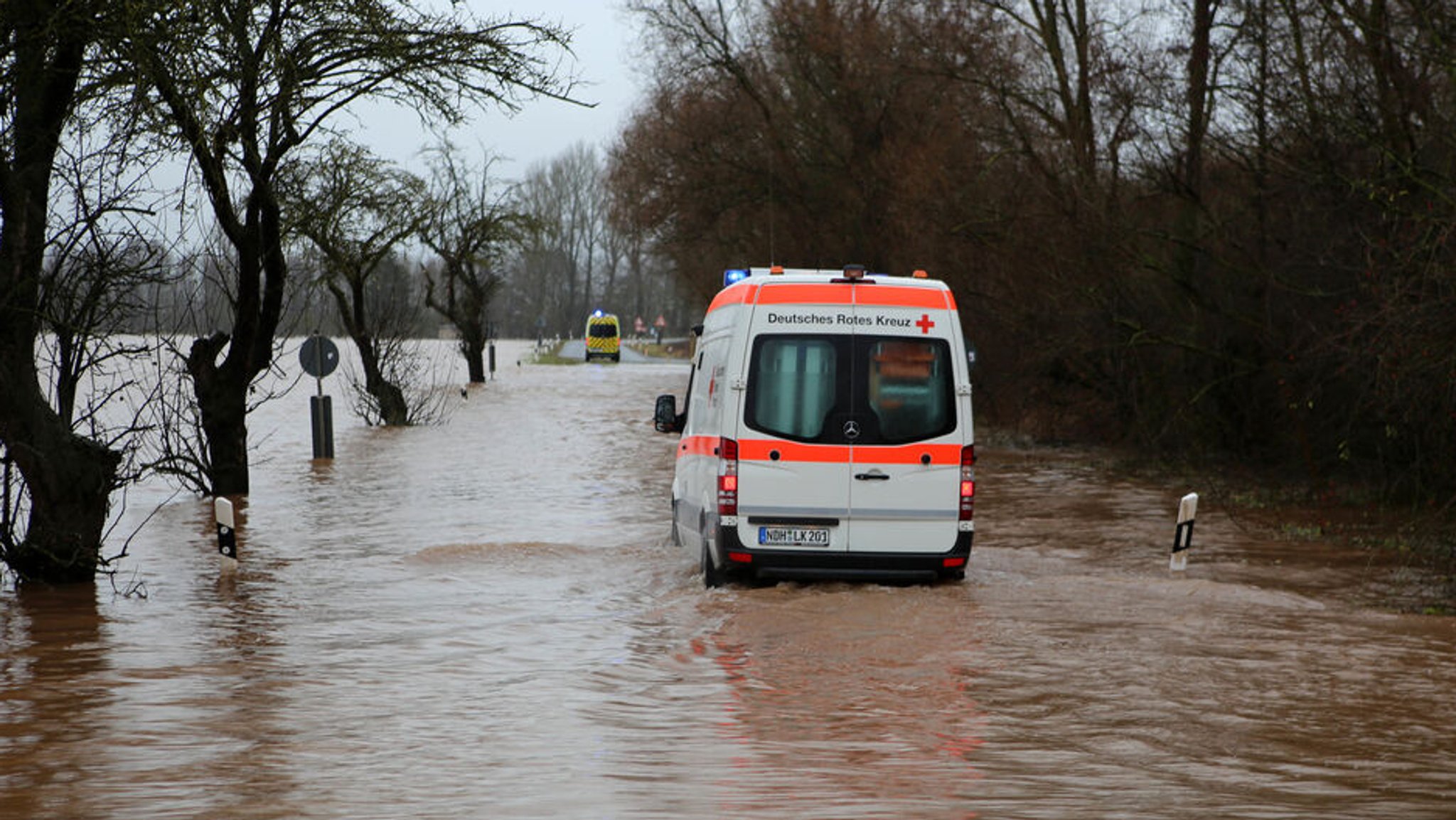 25.12.2023, Thüringen, Windehausen: Ein Krankenwagen fährt über eine von Hochwasser überflutete Straße nach Windehausen. Die Hochwasserlage bleibt in Nordthüringen weiter angespannt. Der Ort Windehausen im Kreis Nordhausen ist vom Wasser eingeschlossen und sollte ab Montagmittag komplett evakuiert werde. Foto: Stefan Rampfel/dpa +++ dpa-Bildfunk +++