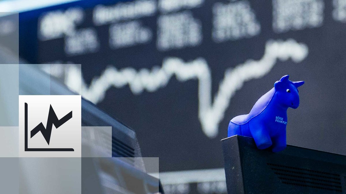 : ein blauer Stier aus Gummi sitzt auf der oberen Kante eines Bildschirmes, im Hintergrund die Kurstafel der Börse