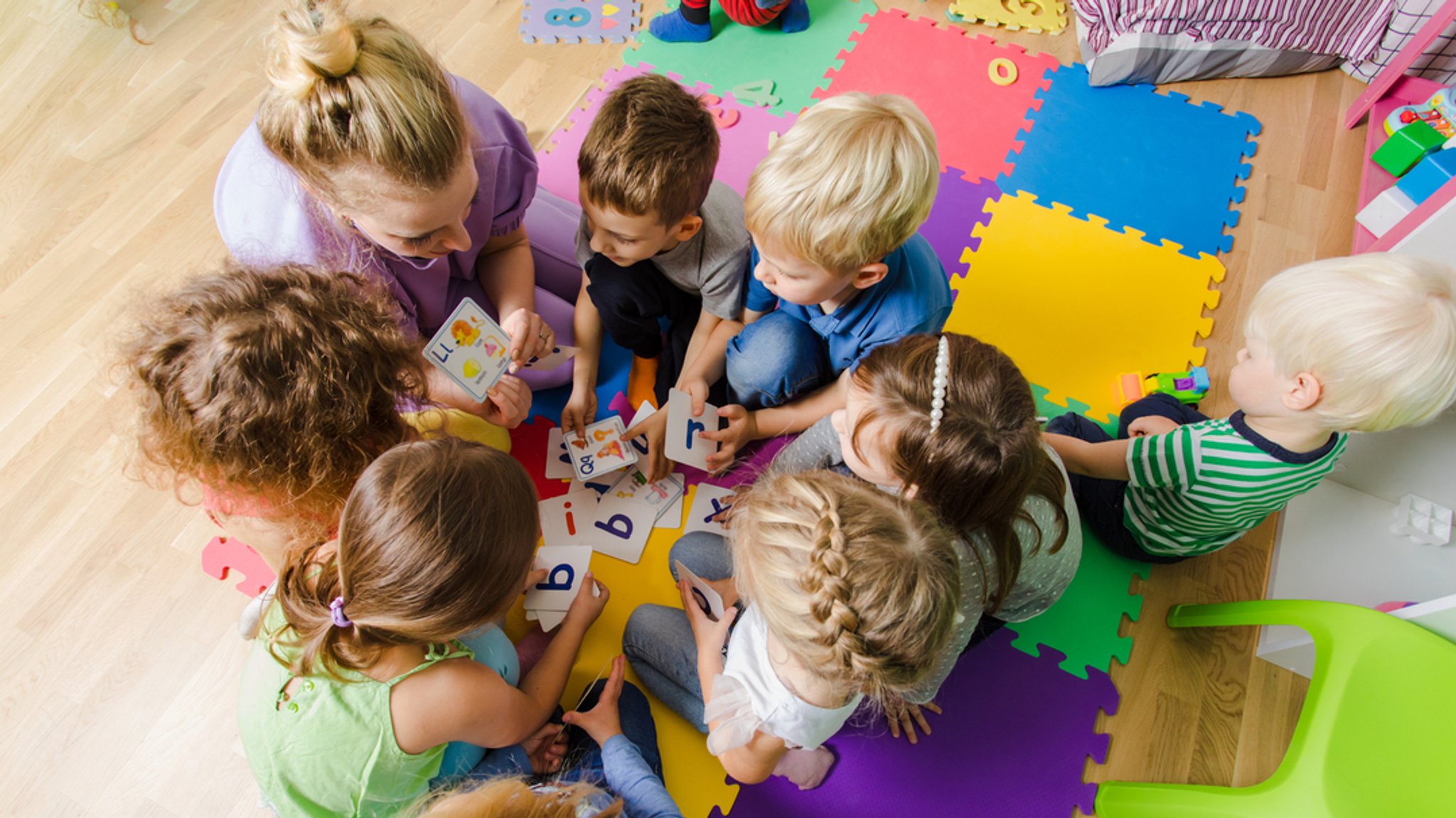 Eine Erzieherin mit einer Gruppe Kinder in einer Kindertagesstätte.