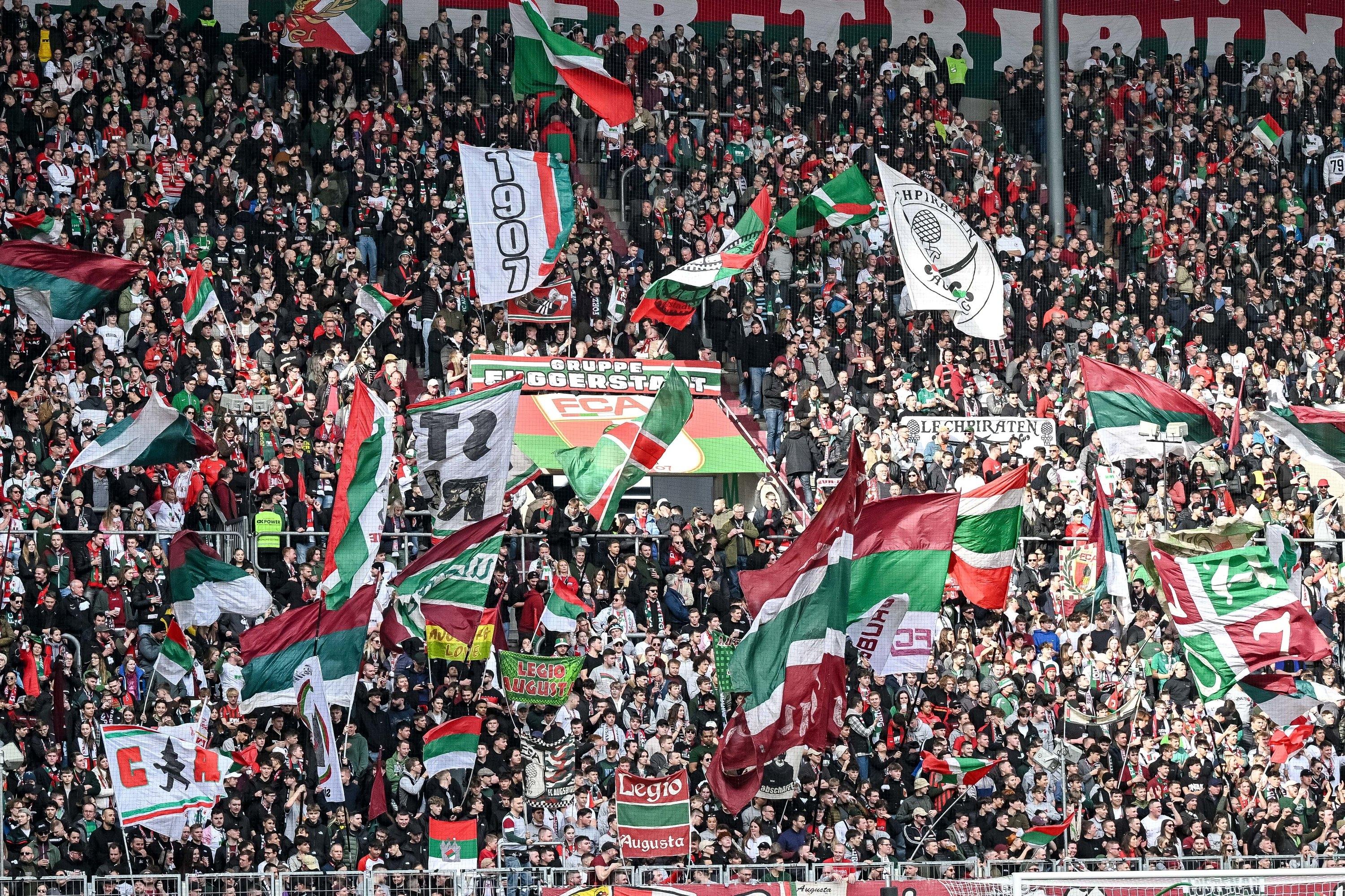 Fans des FC Augsburg schwenken Fahnen in der WWK-Arena. Für einen Ultrafan des FCA gilt für die laufende Bundesliga-Saison allerdings Stadionverbot.