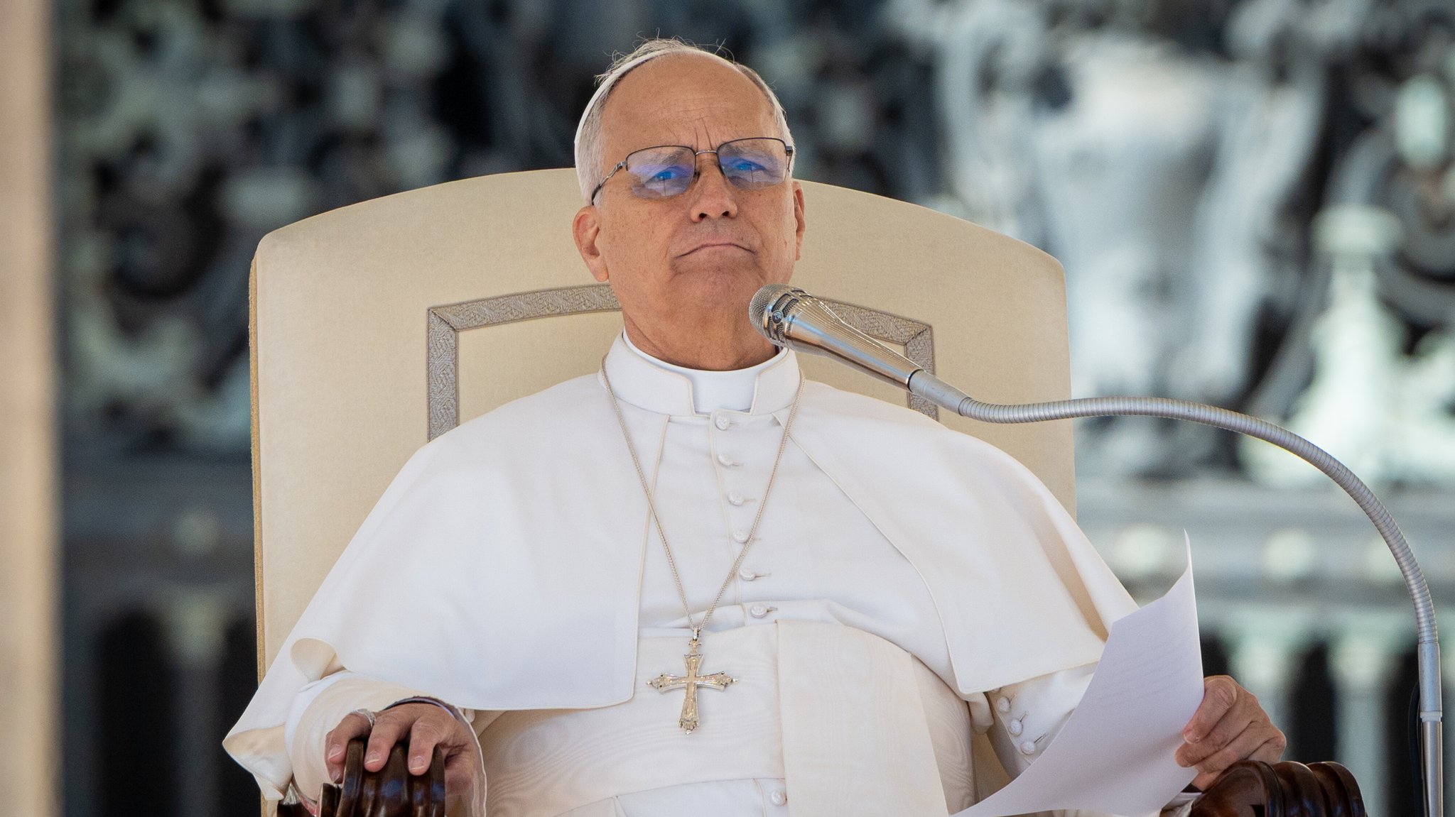 Papst Leo XIV. sitz auf einem Stuhl und hat einen Zettel in der Hand.