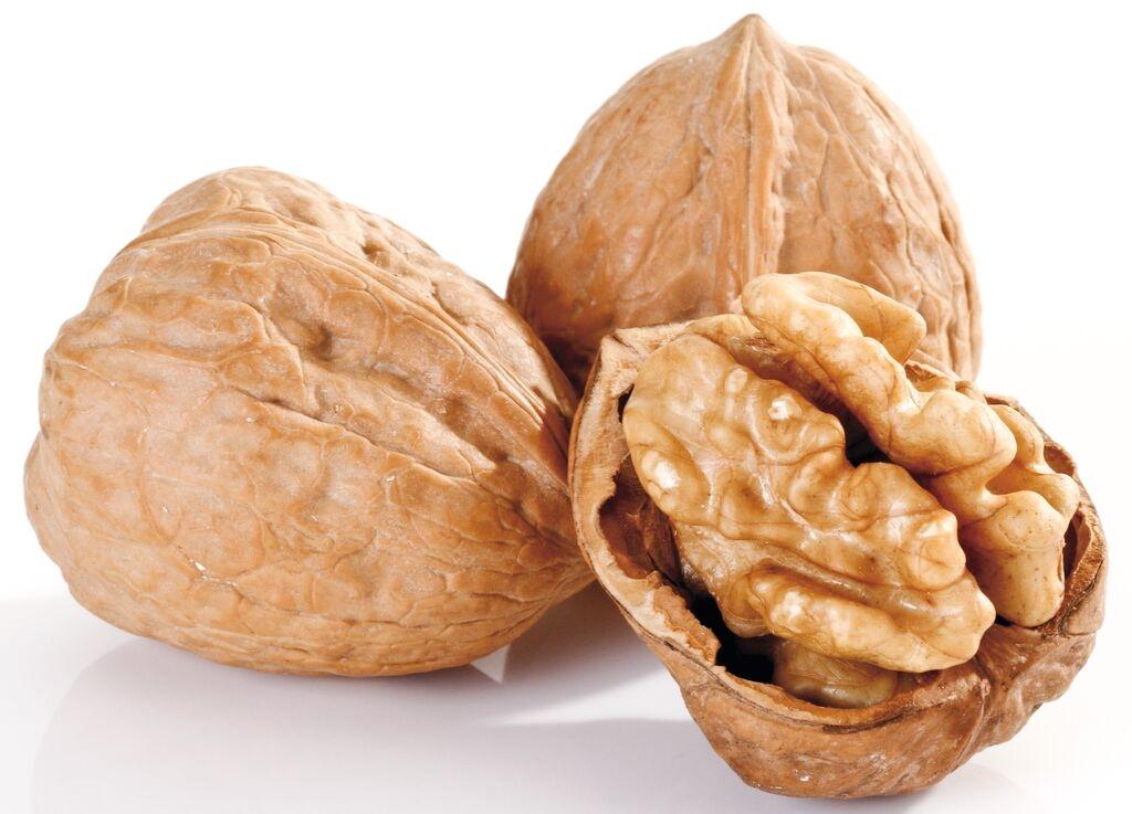 Zwei geschlossene Walnüsse und eine geöffnete Walnuss