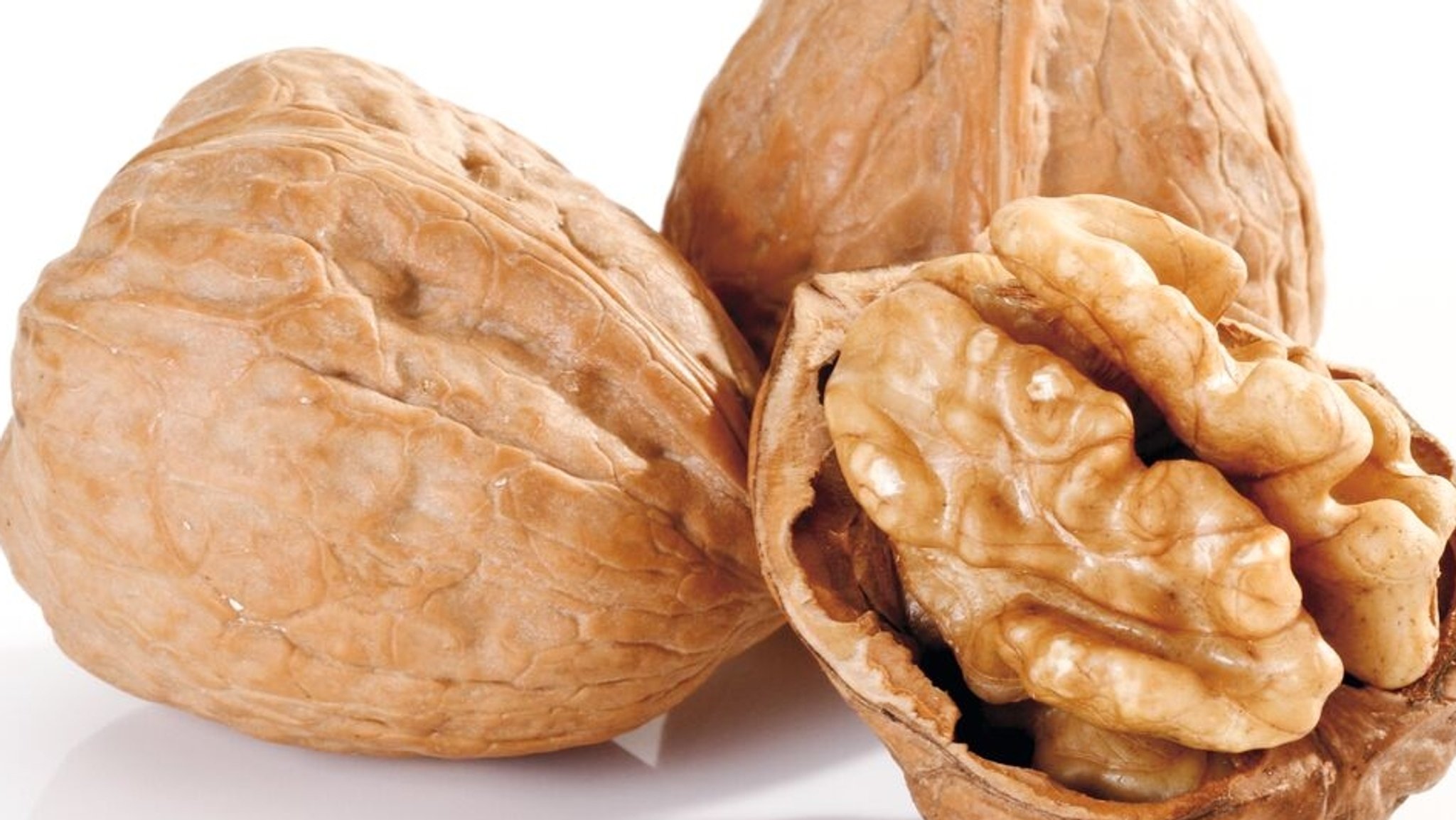 Zwei geschlossene Walnüsse und eine geöffnete Walnuss