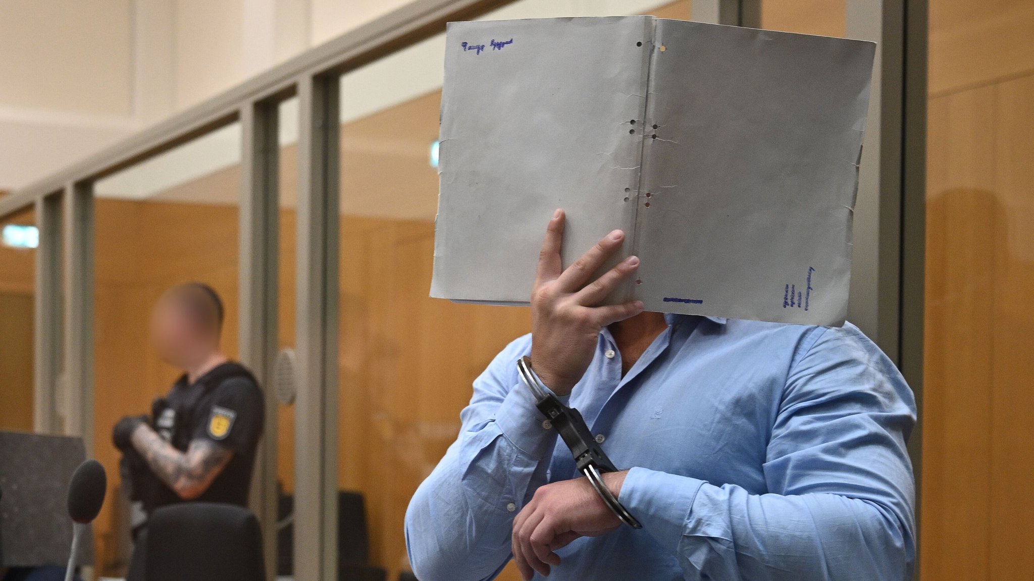 Der Verurteilte verdeckt mit einem Ordner sein Gesicht. | Bild: picture alliance/dpa | Marijan Murat Der Verurteilte verdeckt mit einem Ordner sein Gesicht.