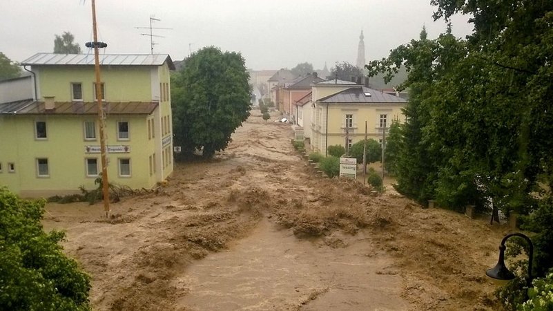 Braune Wassermassen ziehen sich durch eine Straße, Häuser stehen an den Seiten. | Bild: dpa-Bildfunk/Walter Geiring Braune Wassermassen ziehen sich durch eine Straße, Häuser stehen an den Seiten.