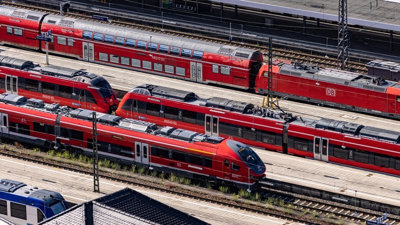 Rote Züge an einem großen Bahnhof.