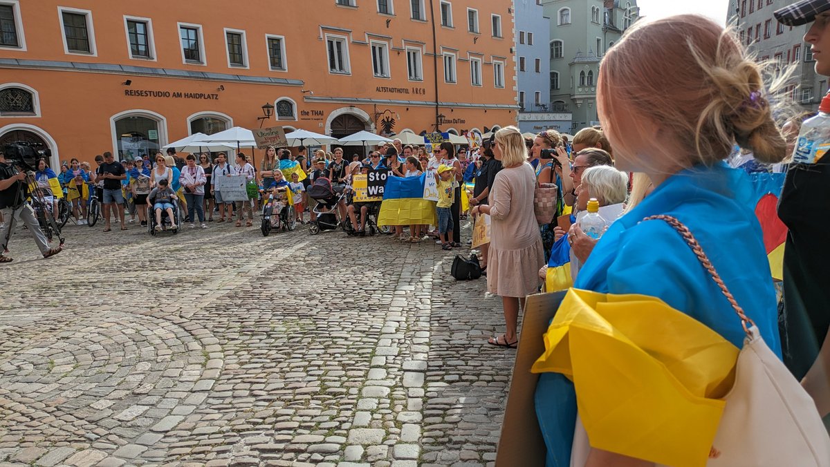 Menschen, versammelt in einer Innenstadt, teils gekleidet in blau-gelben Farben