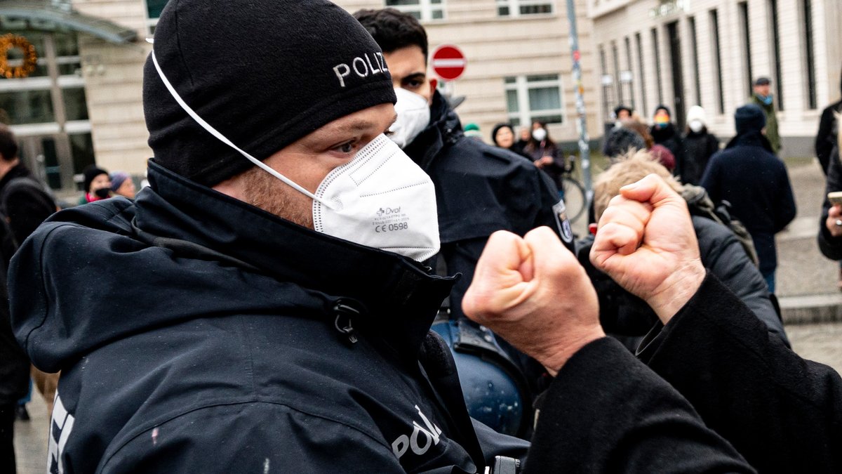 Ein Teilnehmer einer verbotenen Demonstration von Gegnern der Corona-Regeln streckt im Dezember 2021 seine Fäuste einem Polizisten entgegen. 