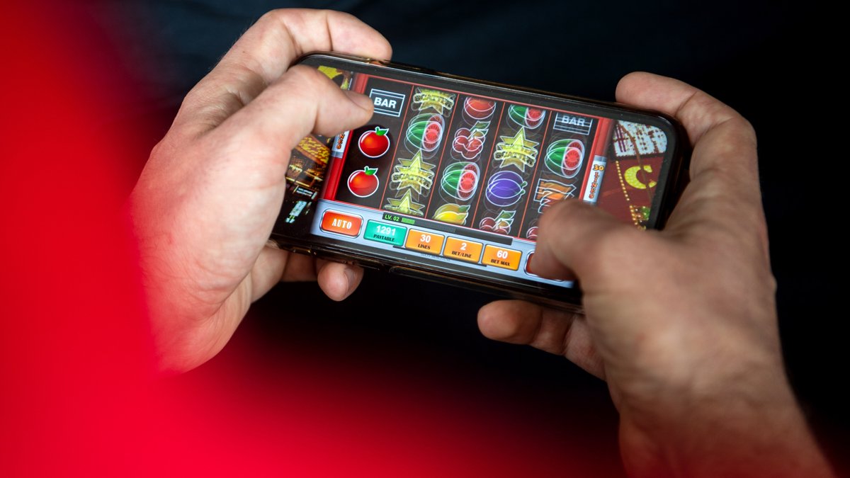 Eine Person spielt unterwegs am Smartphone ein Online-Automatenspiel.