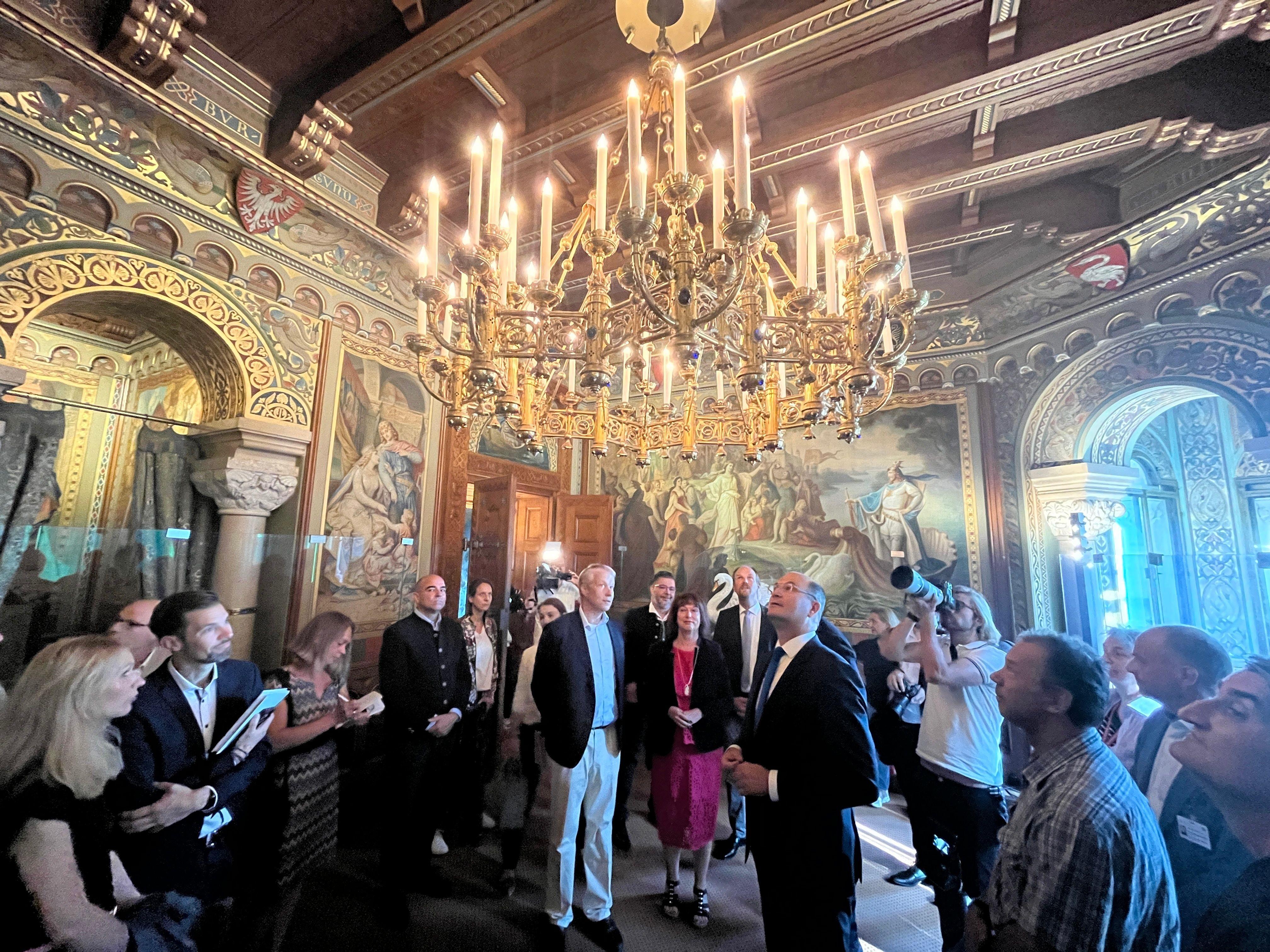 Bayerns Finanzminister Albert Füracker mit Mitarbeitern, Landrätin und Journalisten im restaurierten Wohnzimmer von Schloss Neuschwanstein.