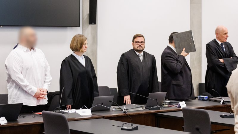 Die Angeklagten Ugur T. (weißes Hemd, gepixelt) und Dejan B. (Ordner vor dem Gesicht) mit ihren Anwälten vor dem Landgericht Nürnberg-Fürth.
