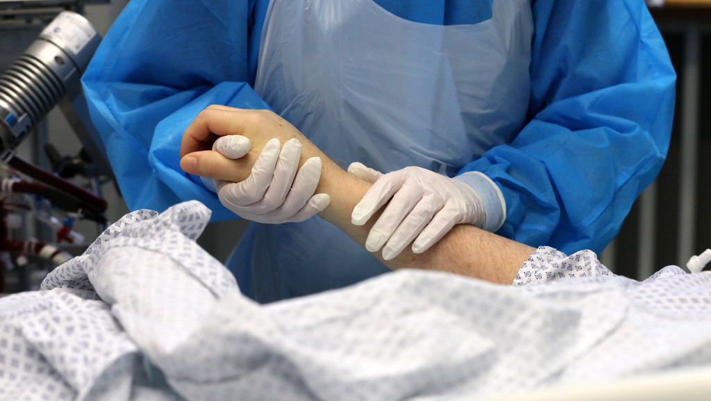 Eine Person vom Krankenhaus-Personal hält die Hand eines Patienten.