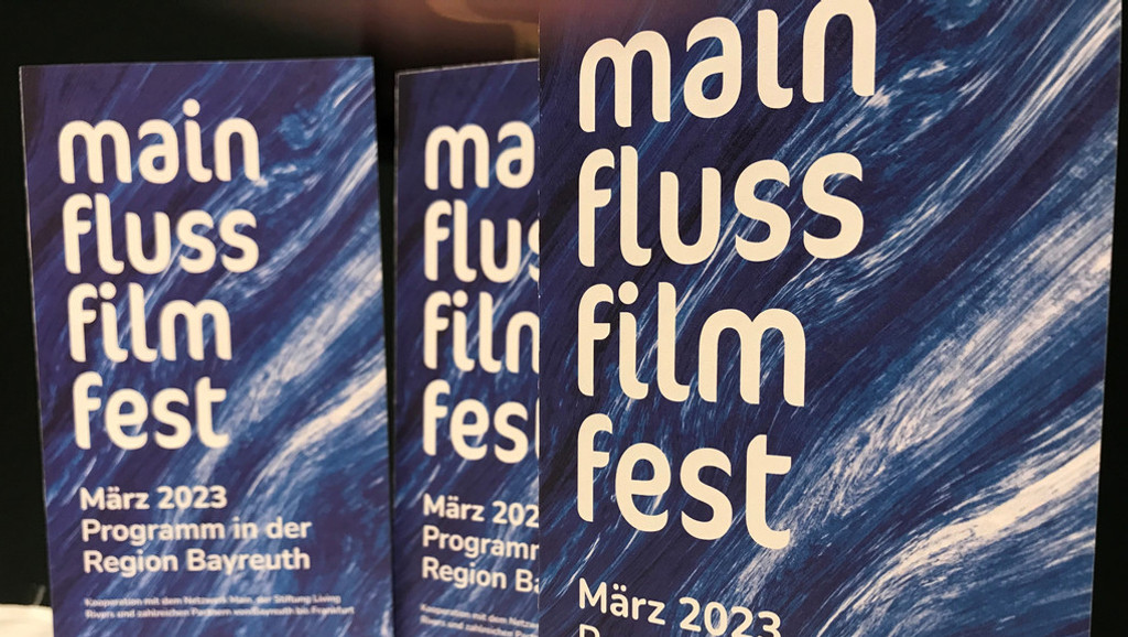 Blaue Flyer des "MainFlussFilmFests" stehen auf einem Tisch.