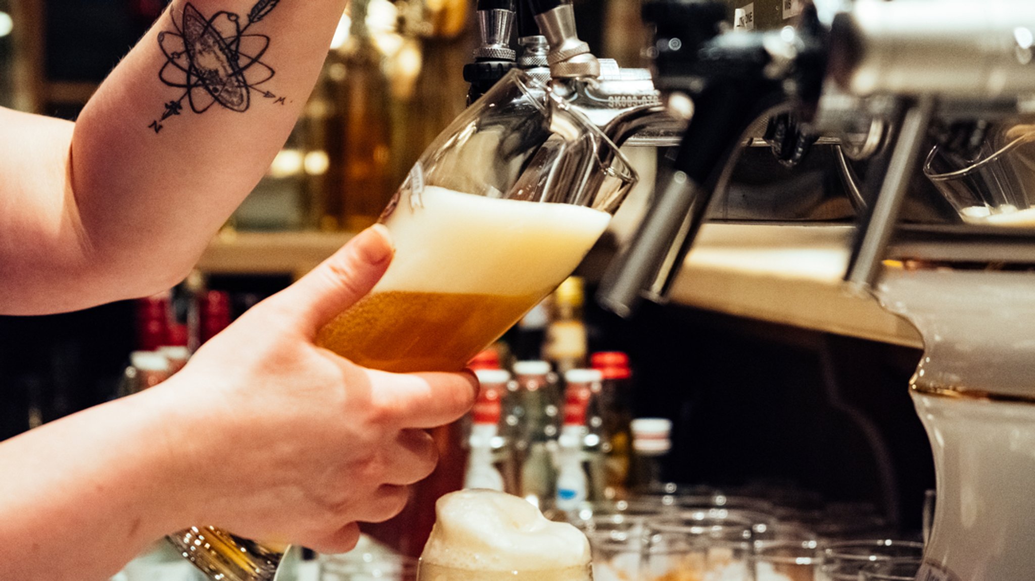 Die Wirtin schenkt Weißbier an der Zapfanlage aus. (Symbolbild)