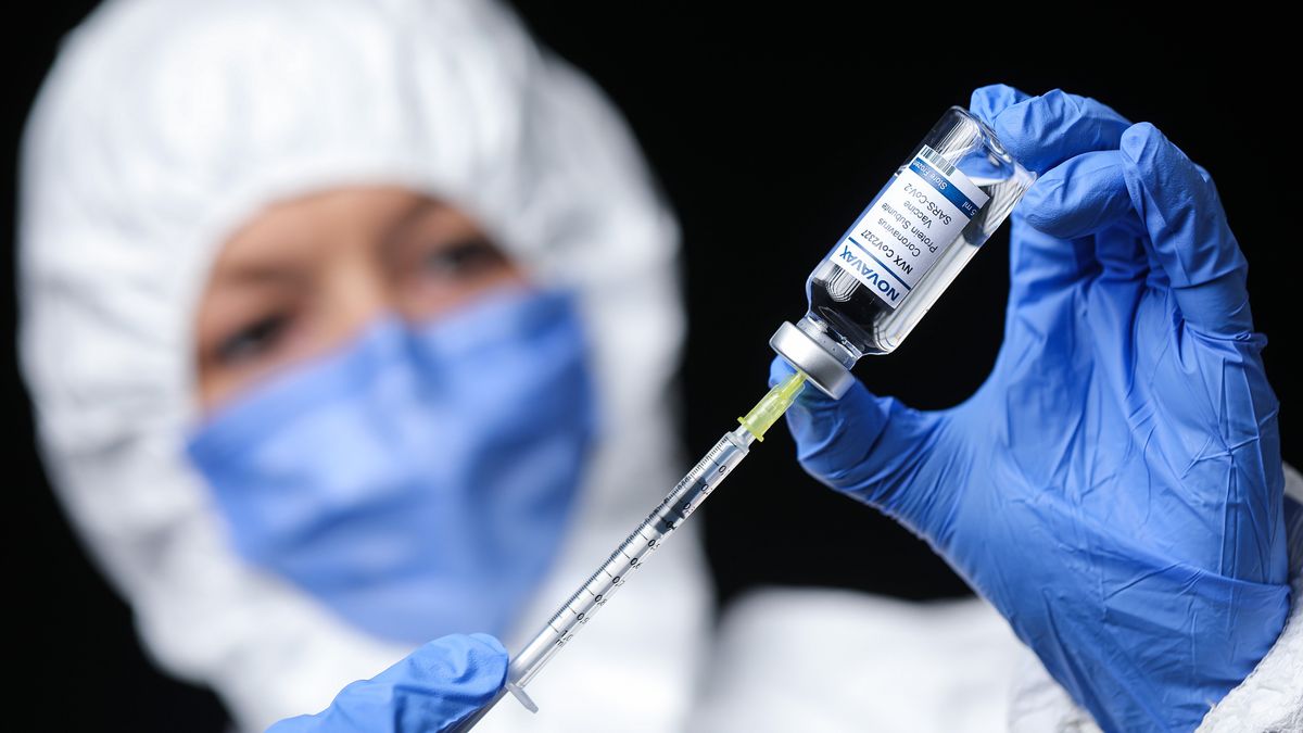 Person in Schutzkleidung zieht ein Spritze mit dem Impfstoff von Novavax auf.