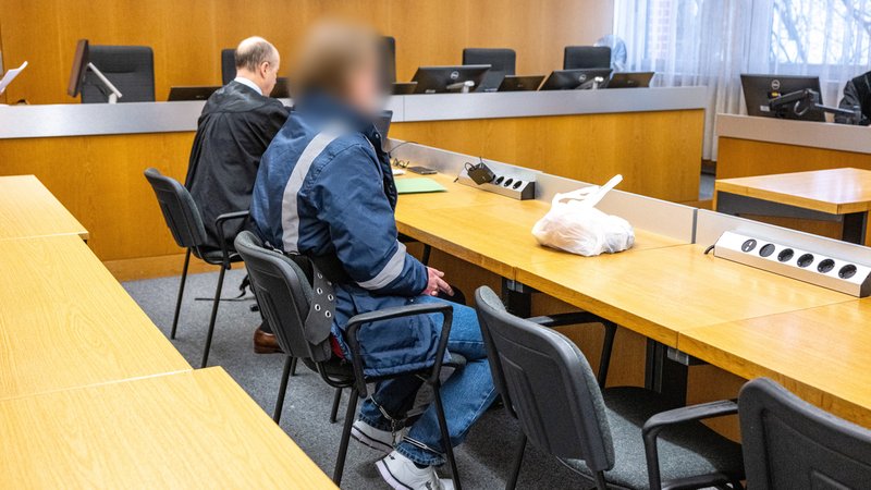 Der Angeklagte sitzt an Händen und Füßen gefesselt im Landshuter Gerichtssaal neben seinem Verteidiger. | Bild: pa/dpa | Armin Weigel Der Angeklagte sitzt an Händen und Füßen gefesselt im Landshuter Gerichtssaal neben seinem Verteidiger.