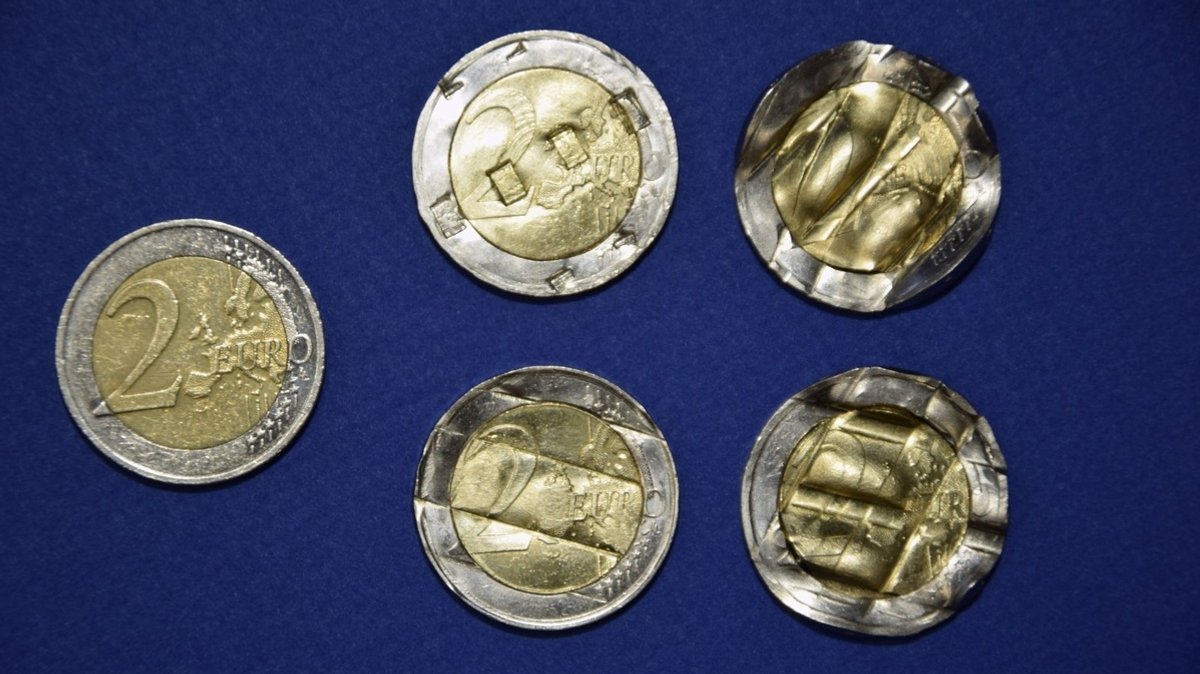 Einige der beschlagnahmten 2-Euro-Stücke im Vergleich zu einer intakten Münze.
