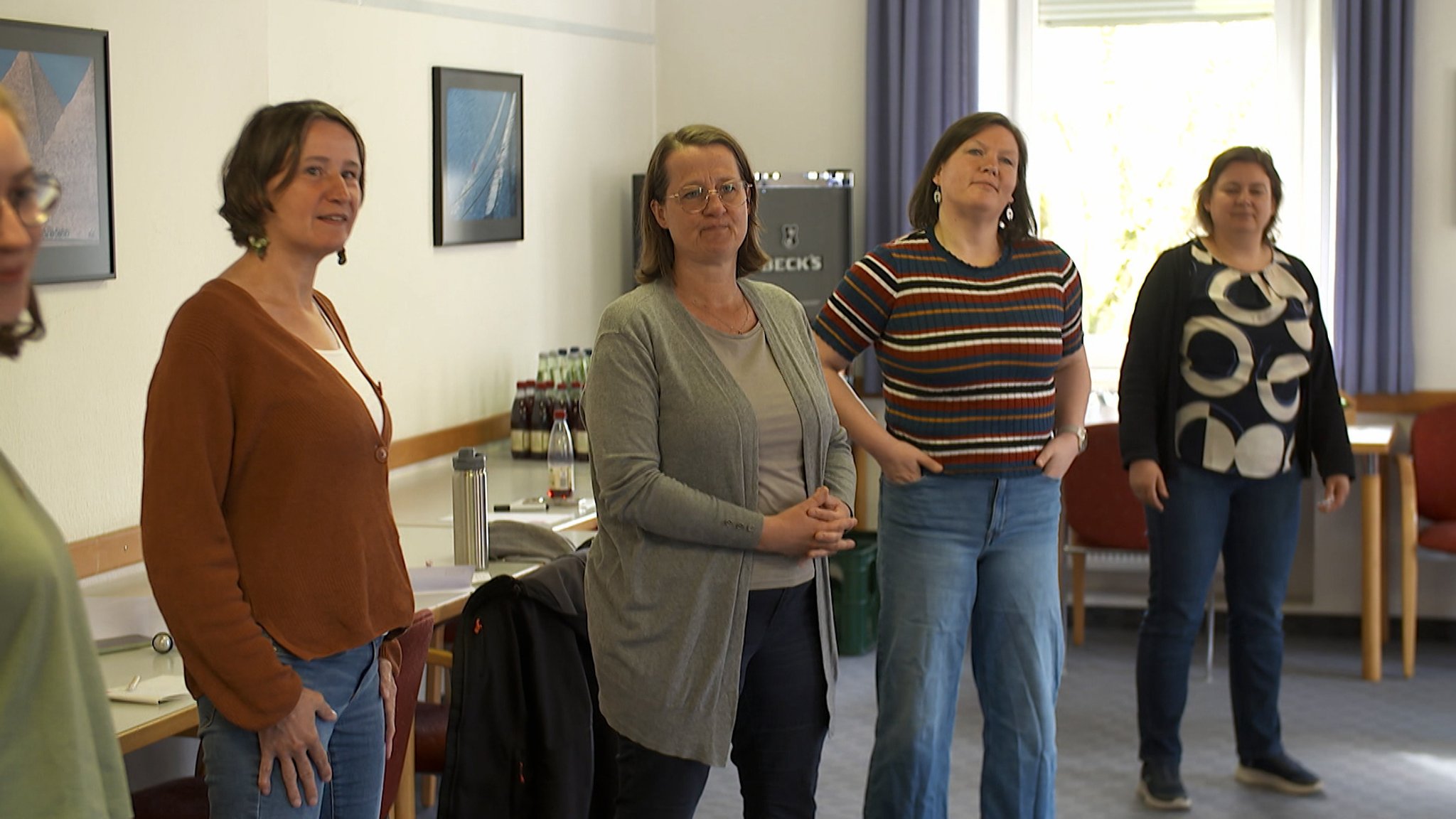 Vier Frauen stehen nebeneinander in einem hellen Innenraum.