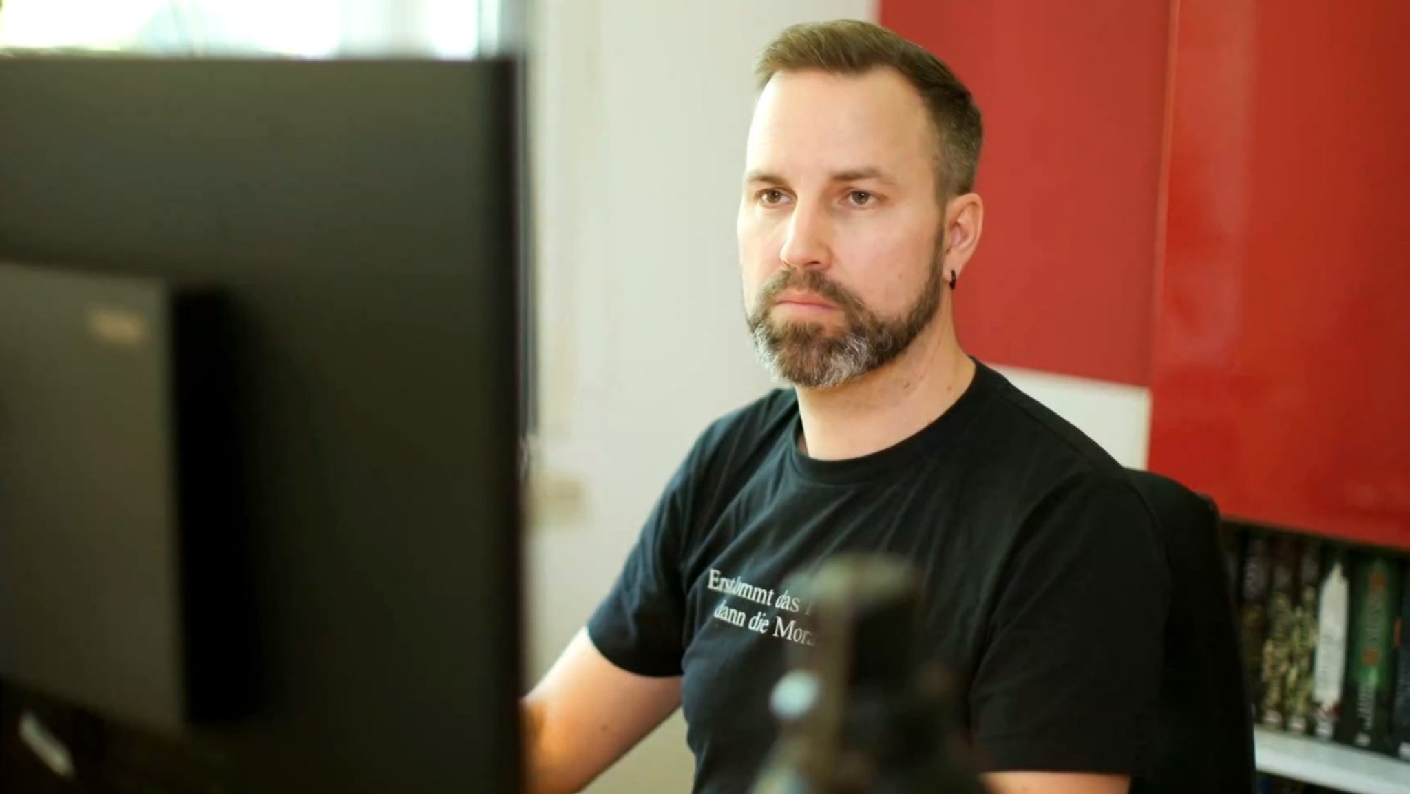 Arbeitender Mann vor einem Monitor.