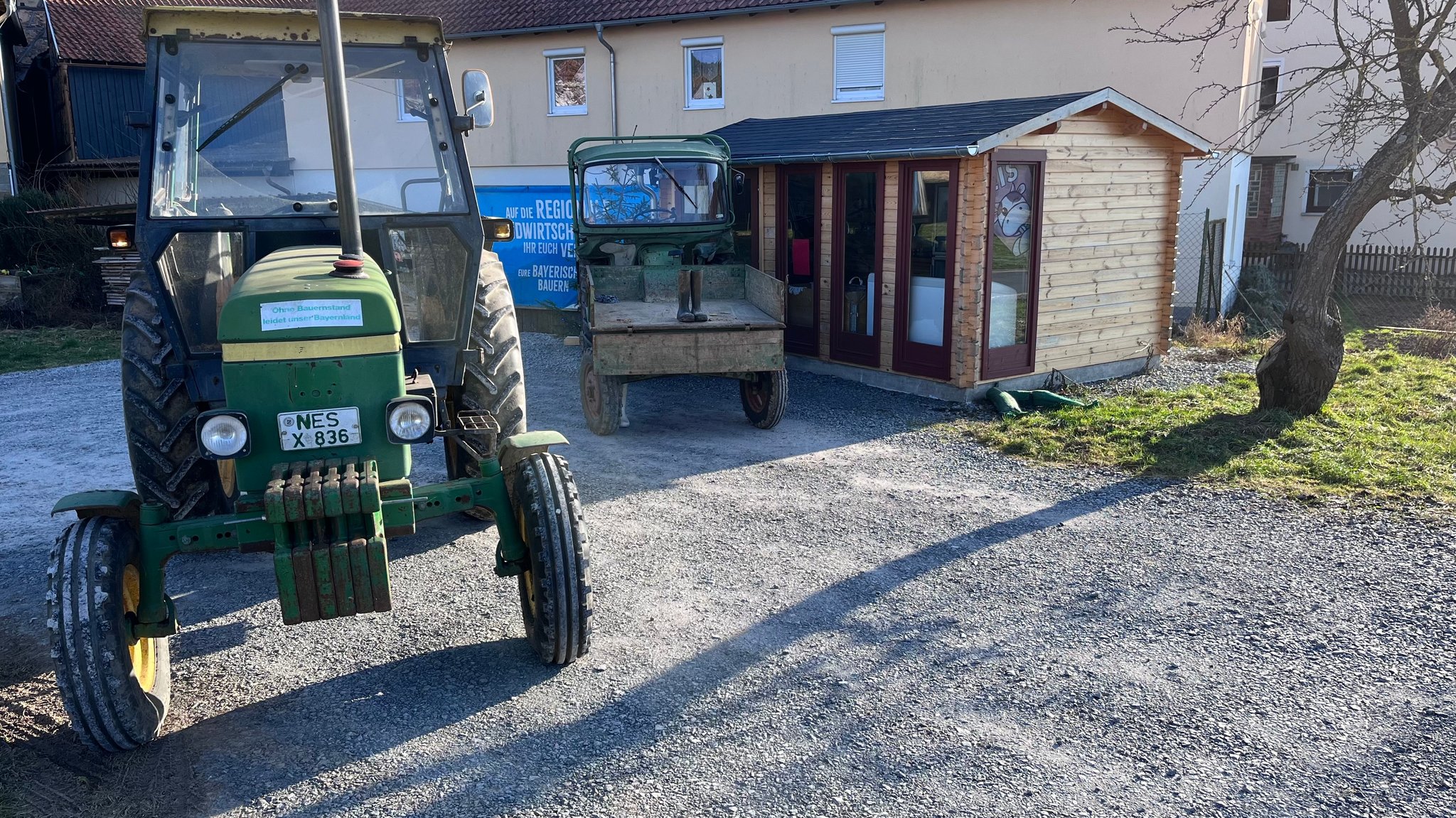 Zwei Traktoren blockieren ein Gartenhäuschen, in dem lokale Nahrungsmittel verkauft werden