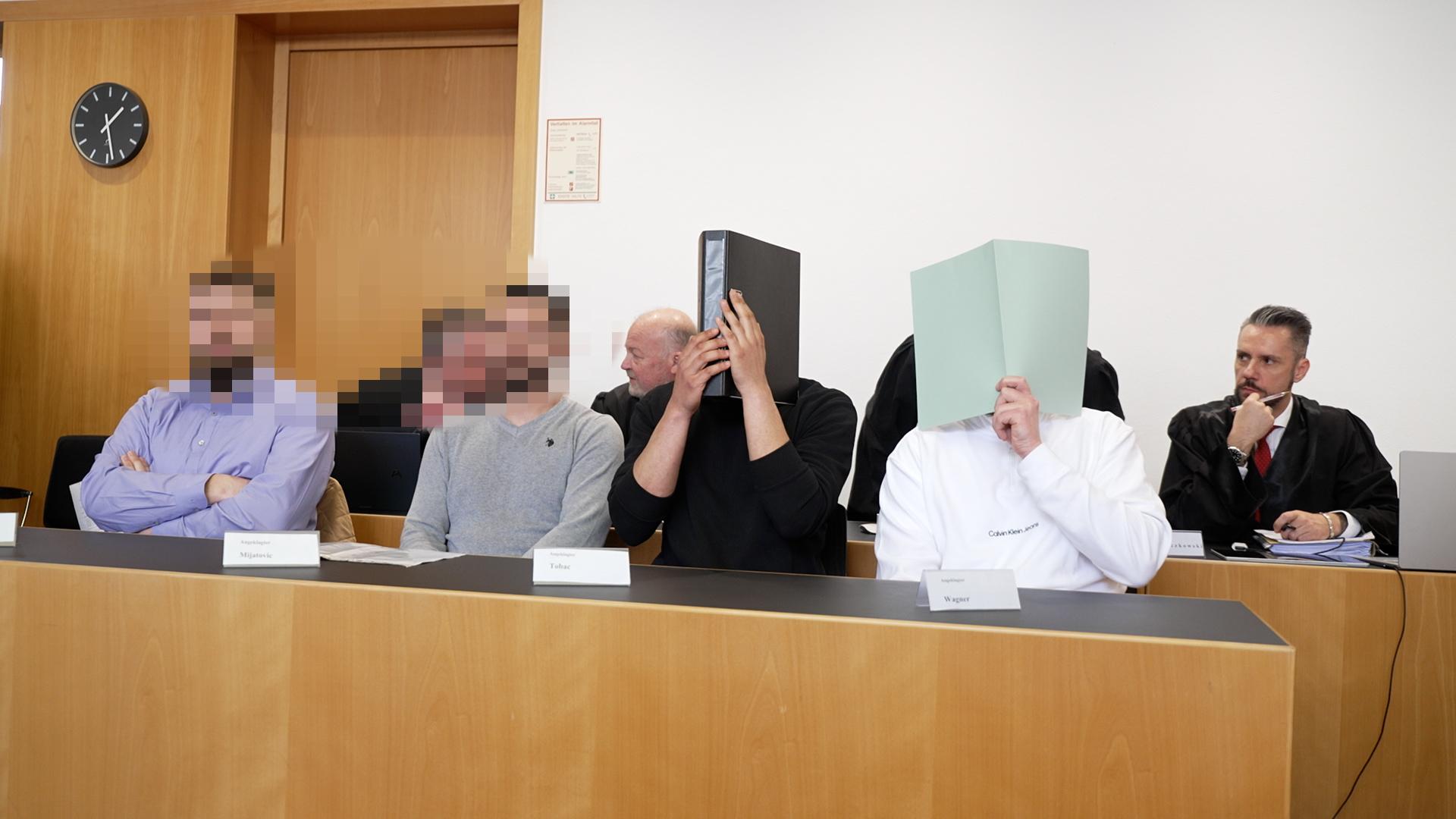 Die Angeklagten im Gerichtssaal des Augsburger Landgerichts. Hinter ihnen ihre Verteidiger.