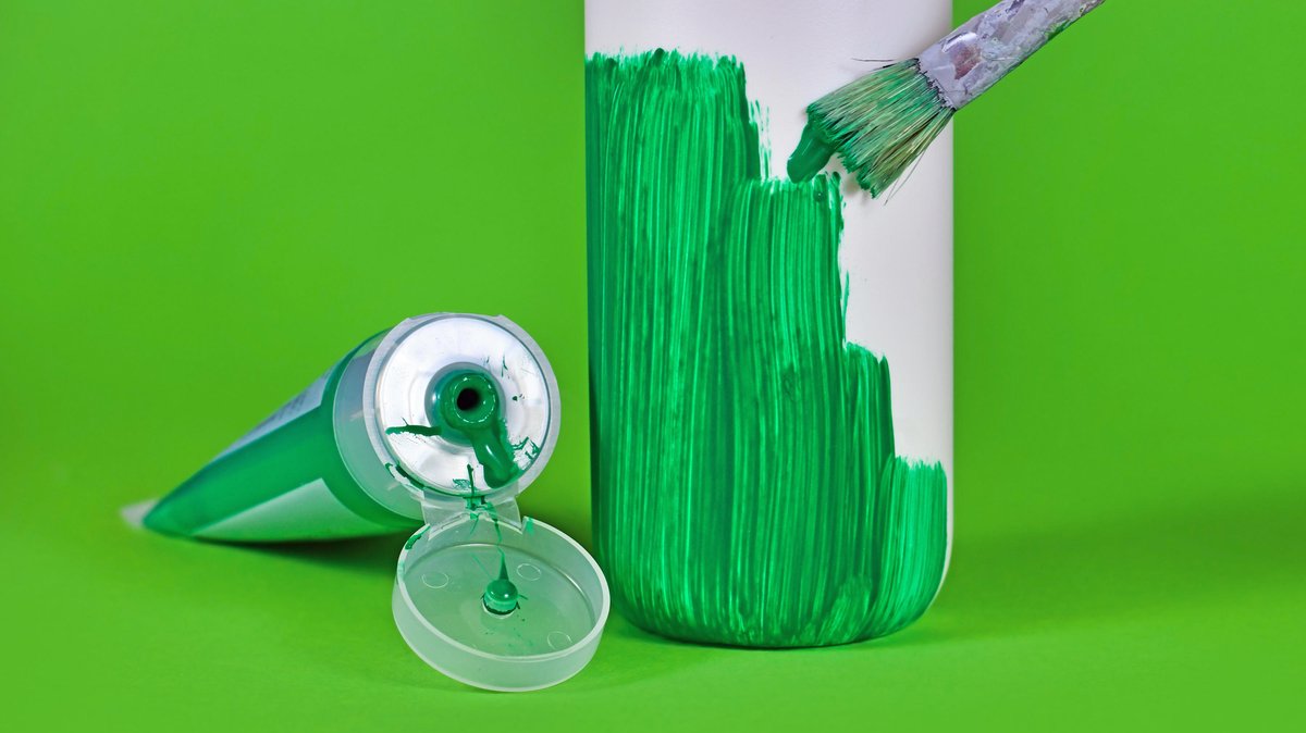 Pinsel bemalt weiße Flasche mit grüner Farbe aus grüner Farbtube