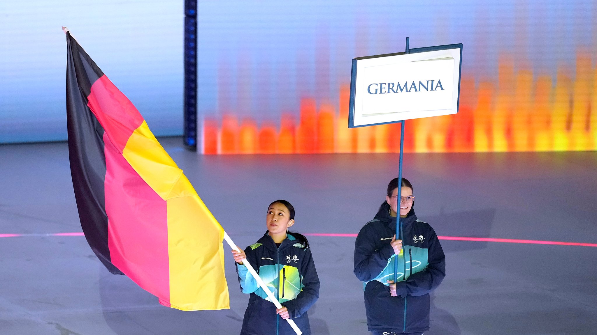 Die deutsche Flagge bei der Eröffnungsfeier der Paralympics 2026 wird von Volunteers getragen.