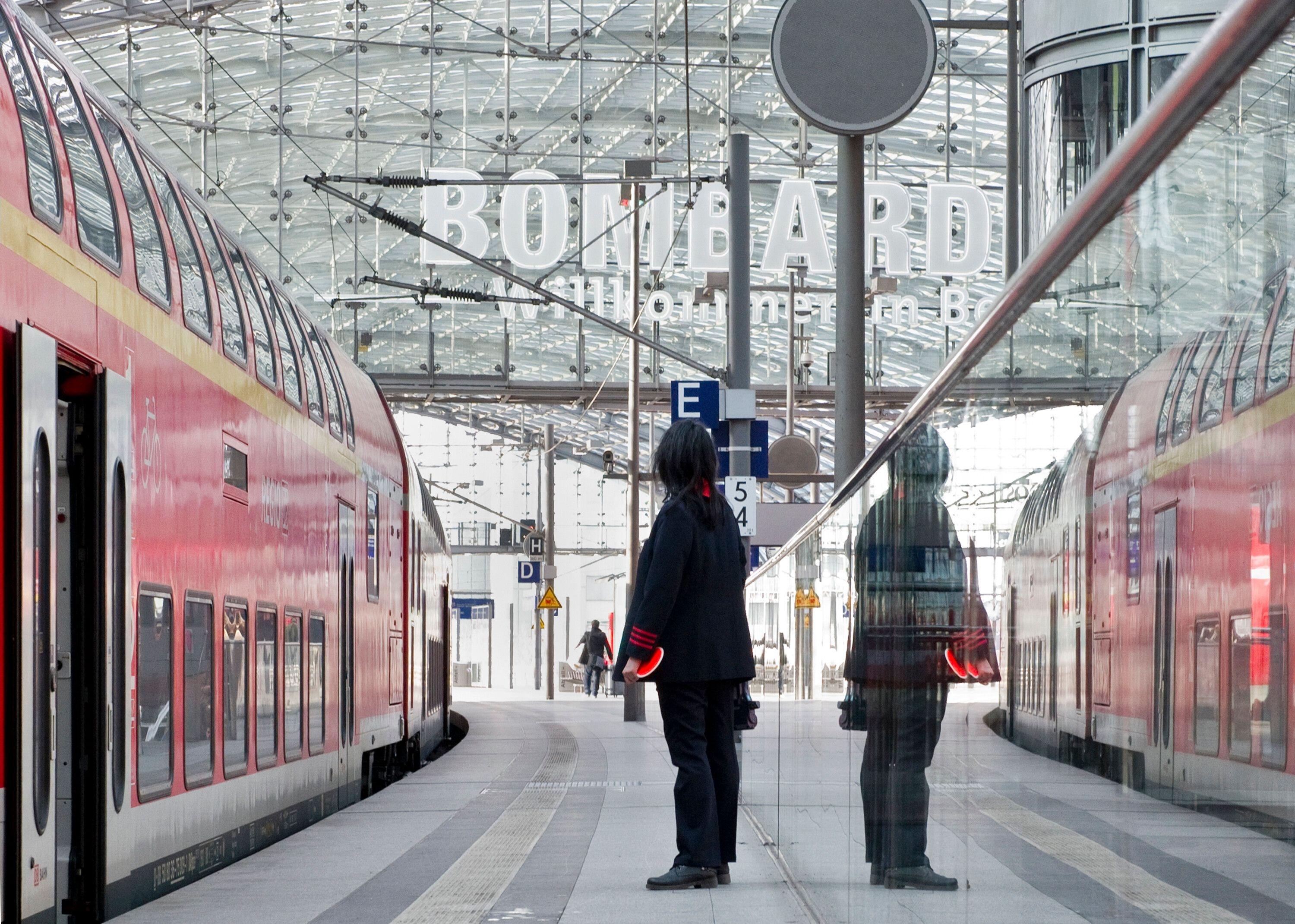 Eine Zugbegleiterin steht am Bahnhof.