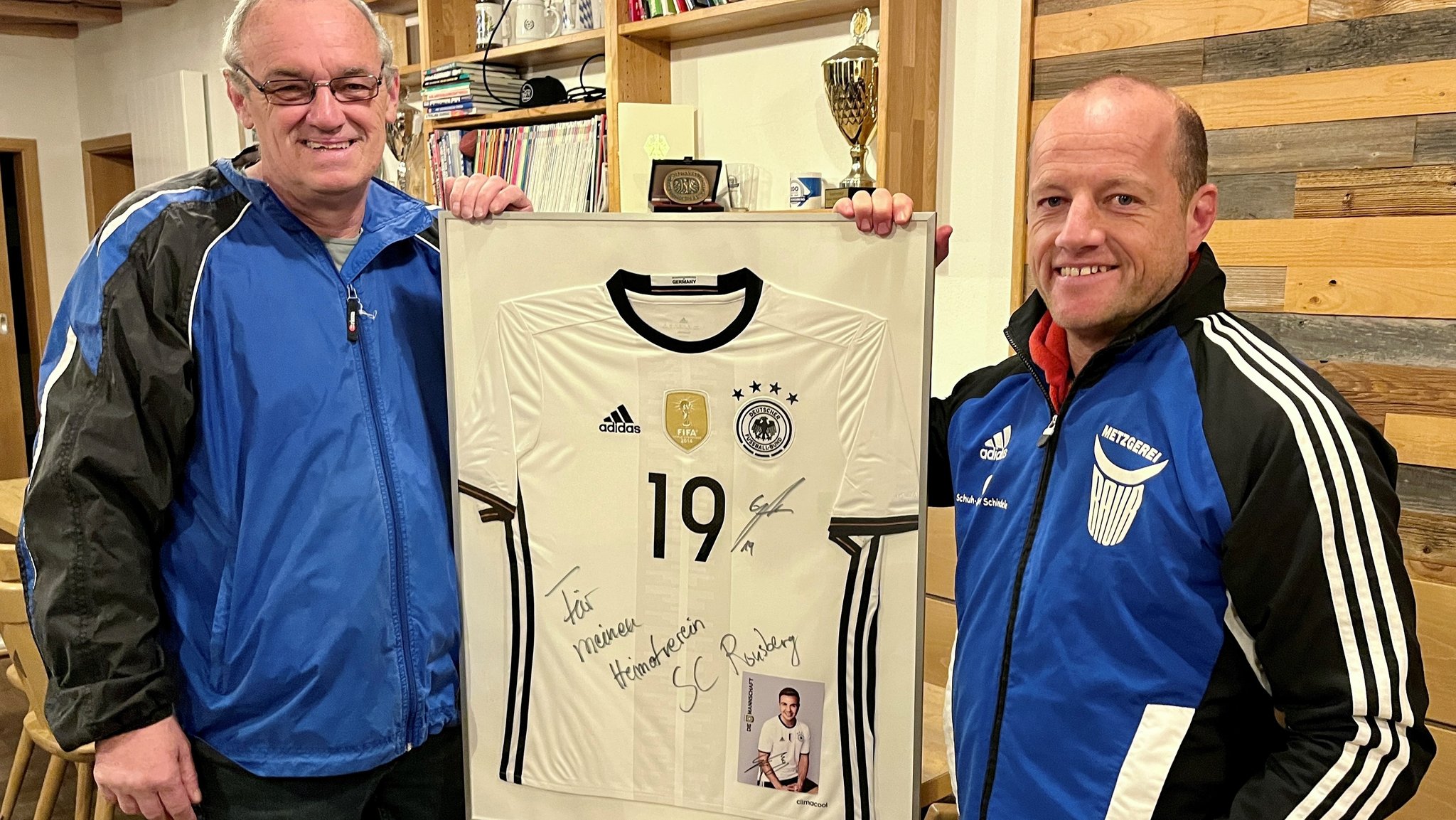 Helmut Albat und Michael Schmalholz zeigen ein Nationalmannschafts-Trikot von Mario Götze im Vereinsheim des SC Ronsberg. 