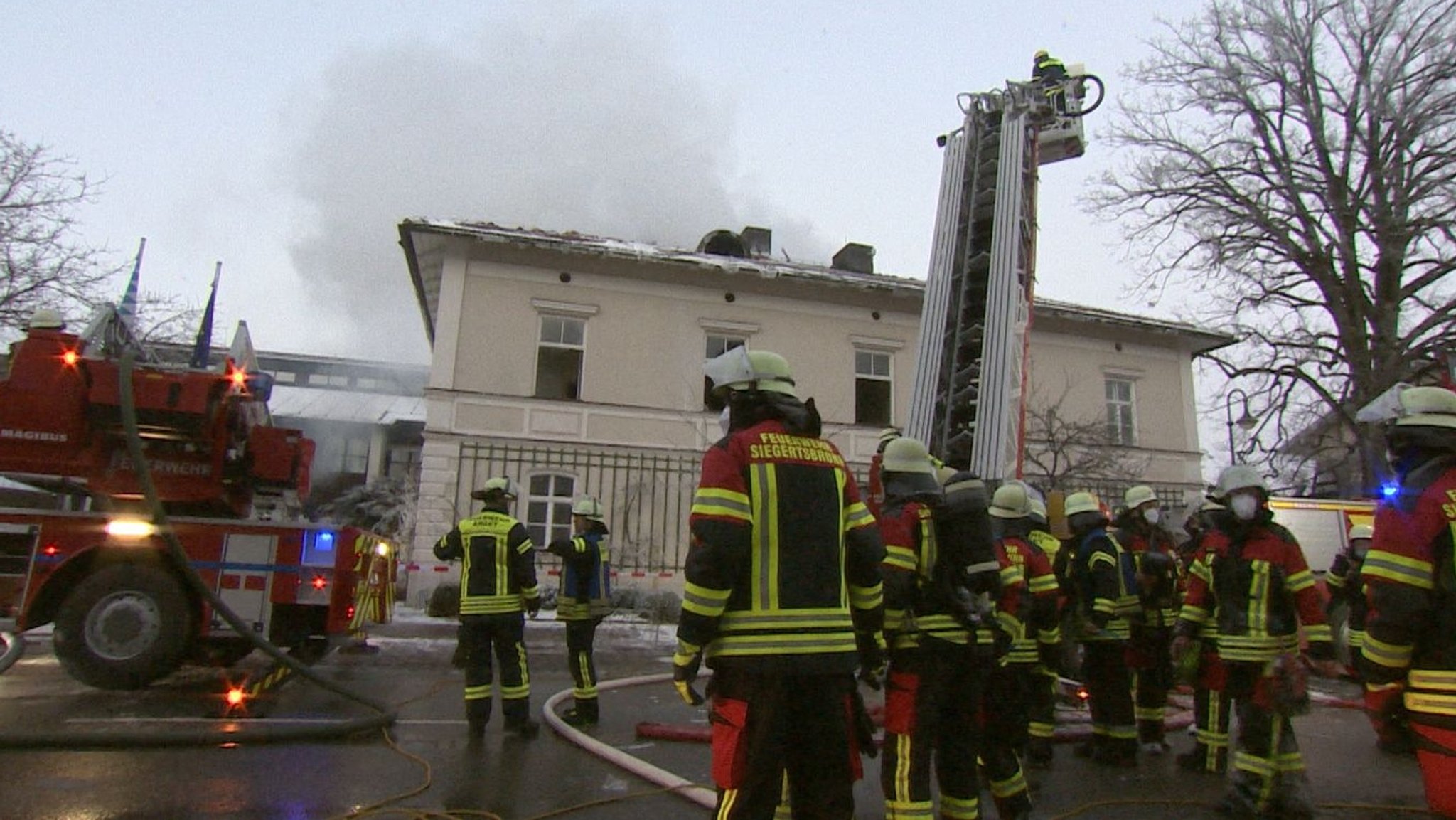 Feuerwehrwehr vor dem alten Rathaus. Aus dem Haus steigt Rauch auf.