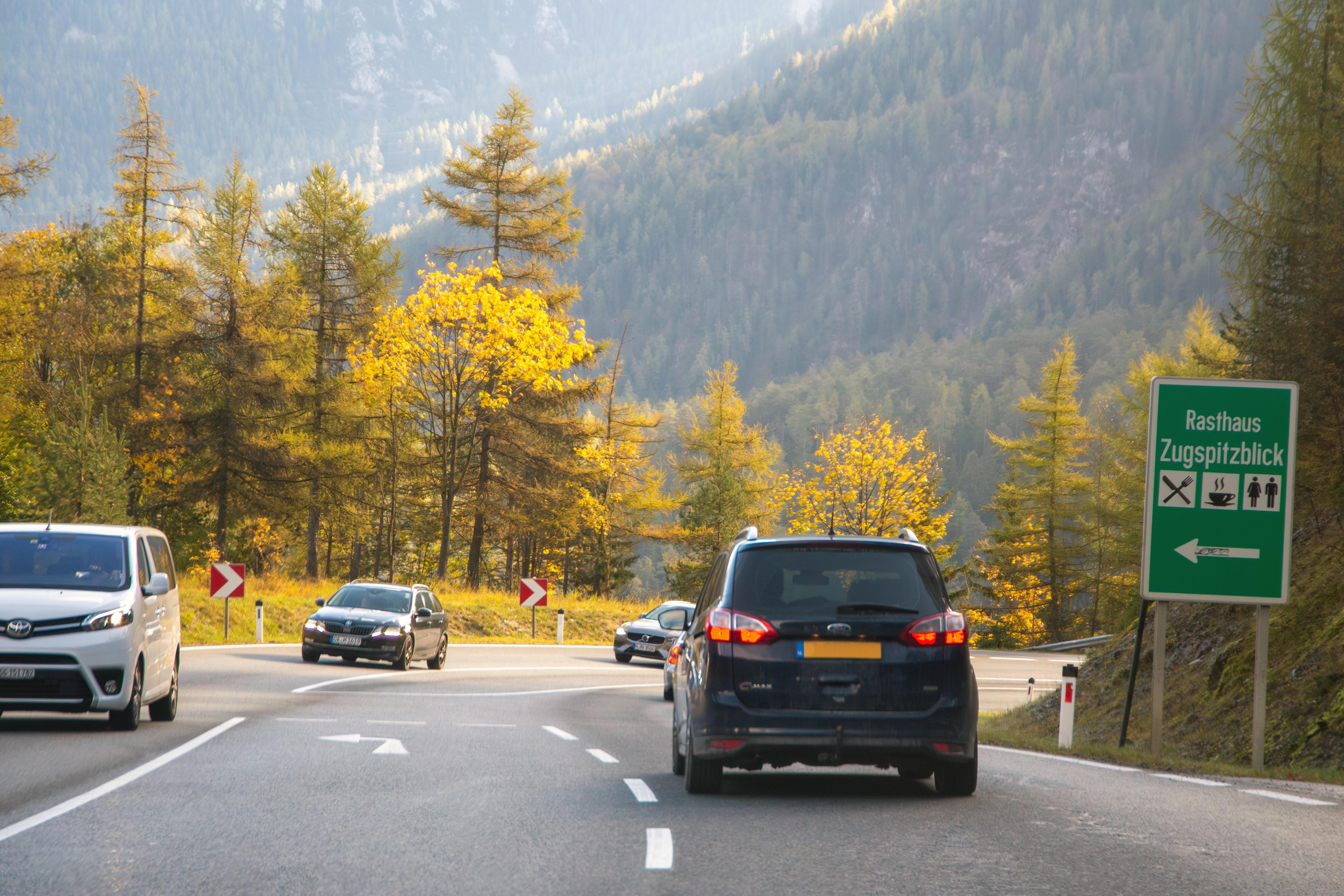 Autos fahren auf der Straße, der über den Fernpass in Tirol führt. Im Hintergrund bewaldete Berghänge.
