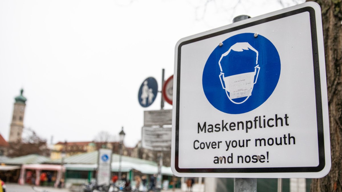 Schild weist am Viktualienmarkt in München auf Maskenpflicht hin.