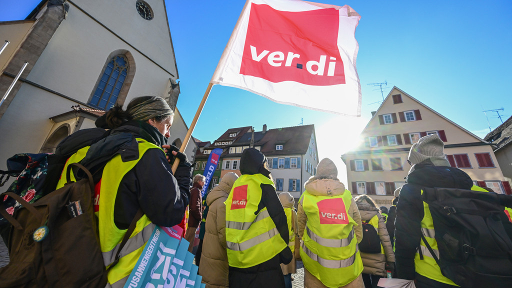 Mitglieder der der Gewerkschaft Verdi stehen bei einer Kundgebung mit Fahnen auf dem Marktplatz in Rottenburg (Symbolbild).