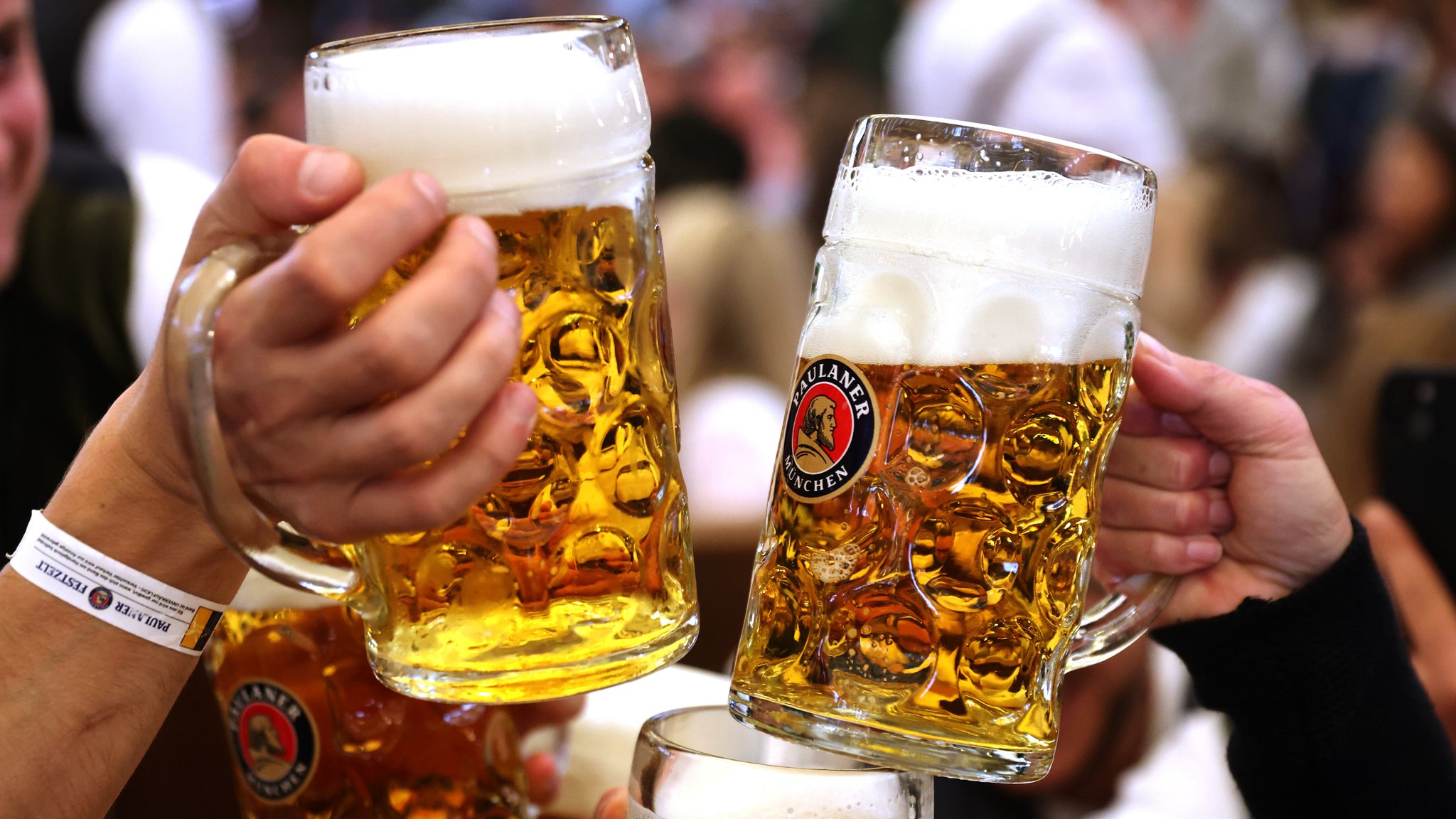 Zwei Oktoberfestbesucher stoßen mit Bierkrügen an.