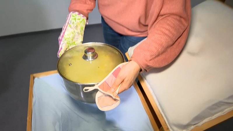 Ein Topf wird in eine Kochkiste gestellt.