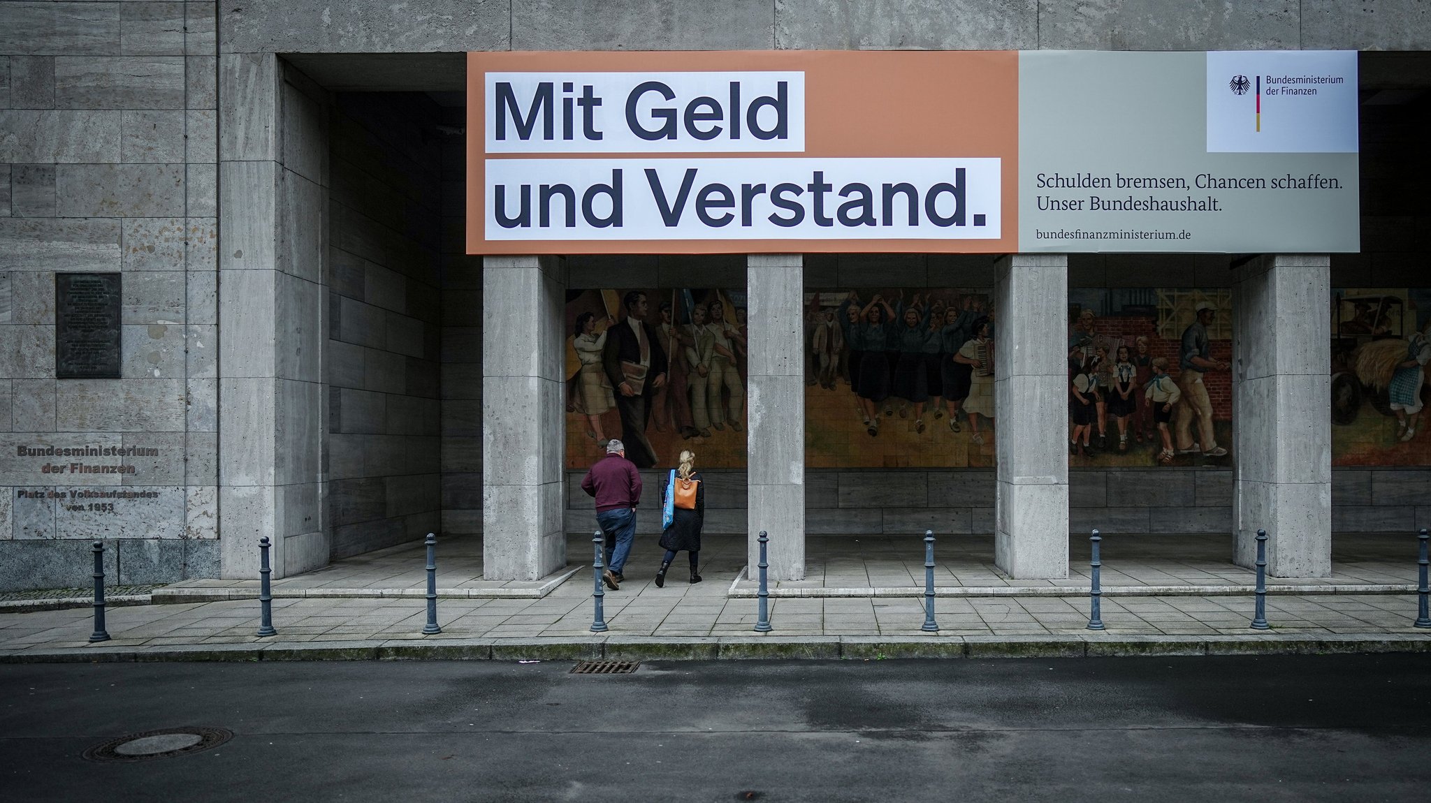 Ein Plakat mit der Aufschrift "Mit Geld und Verstand. Schulden bremsen, Chancen schaffen. Unser Bundeshaushalt." hängt über dem Eingang zum Bundesministerium der Finanzen in Berlin.