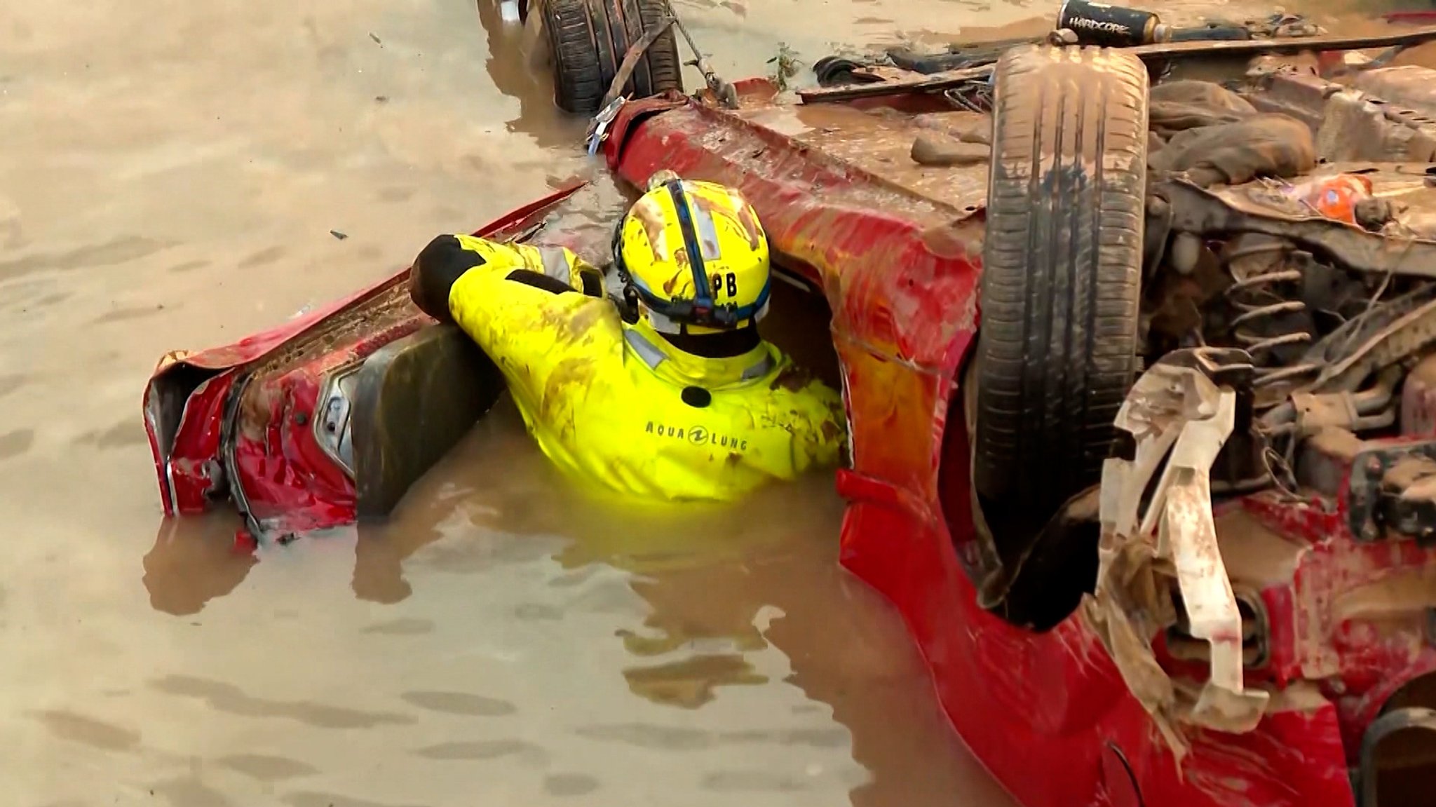 Eine Rettungskraft an einem Auto im Überschwemmungsgebiet.