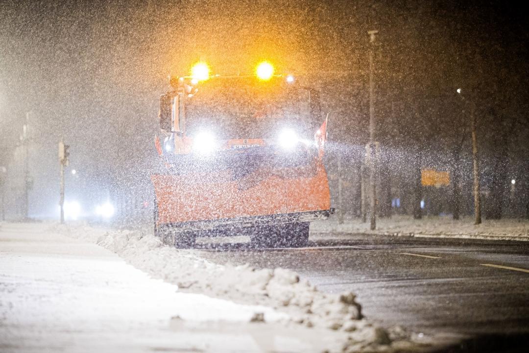 Ein Streufahrzeug ist am frühen Morgen im dichten Schneefall im Einsatz