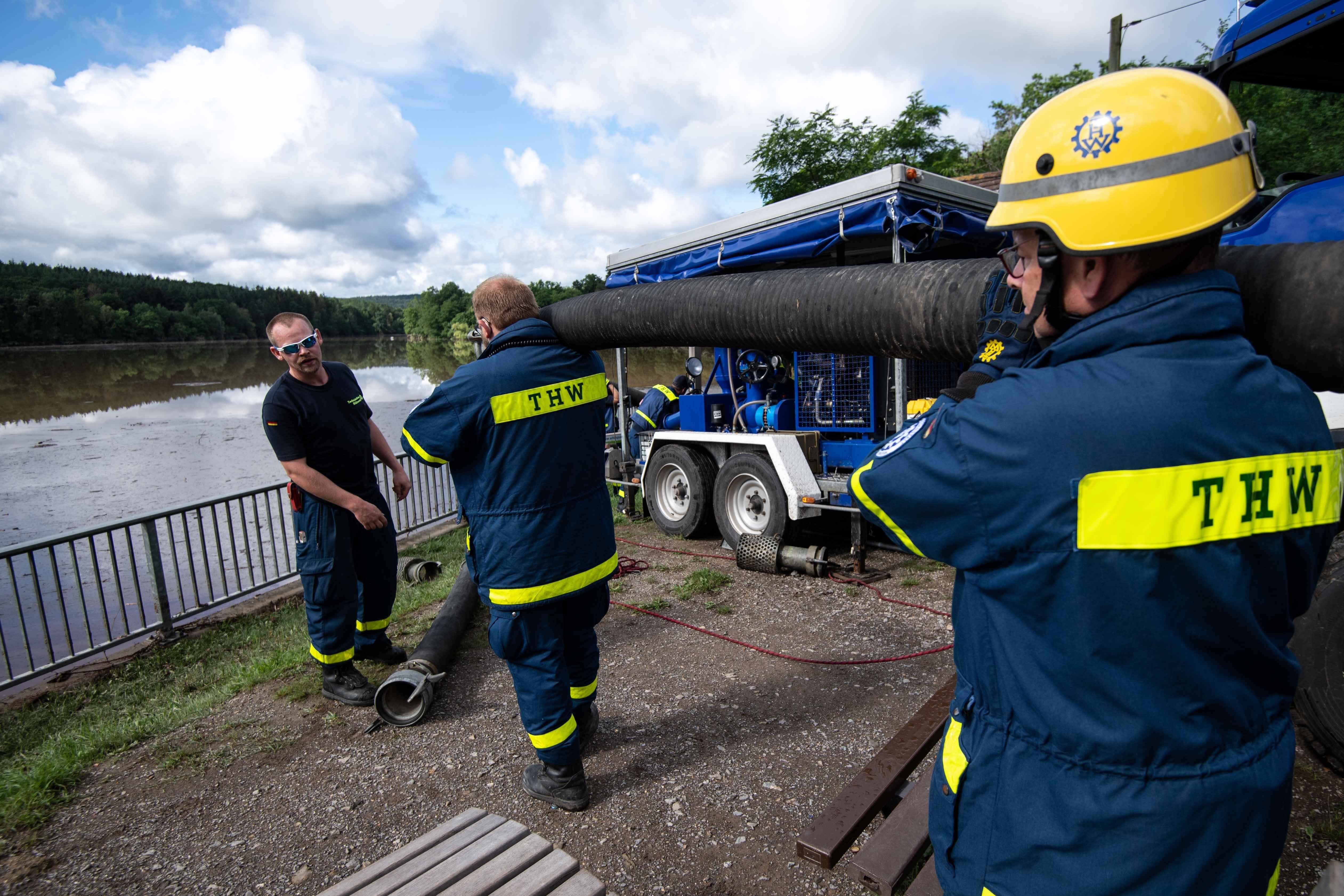 Helfer des Technischen Hilfswerks (THW) schleppen Schläuche.  | Bild:pa/dpa/Marius Becker