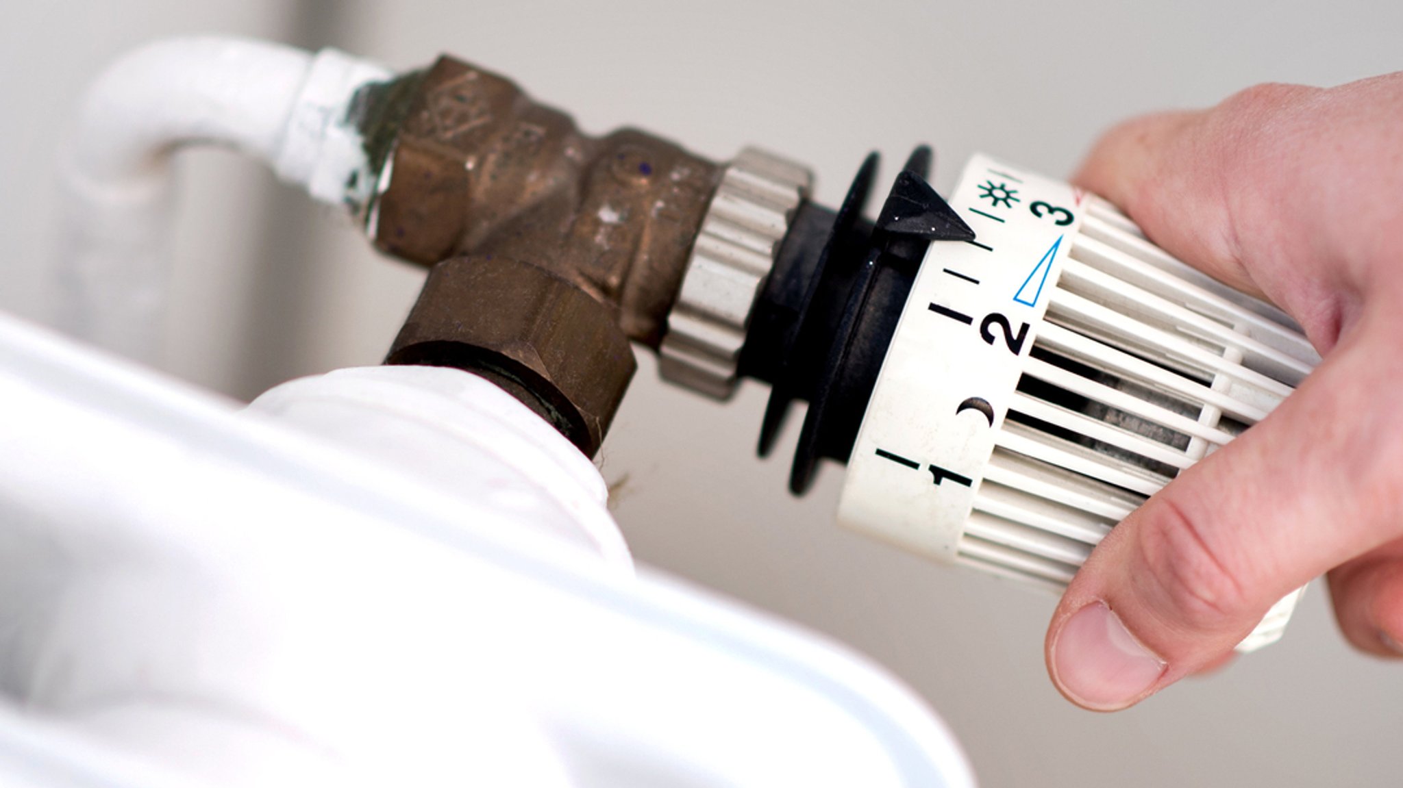 Hand an einem Heizungsthermostat.