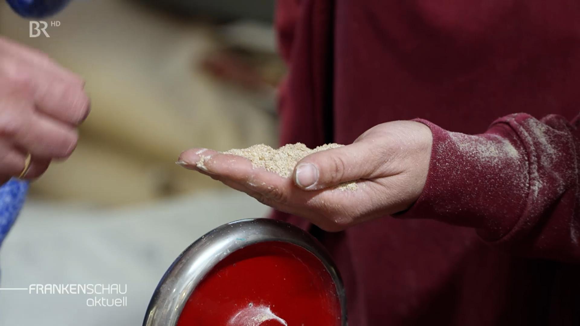Eine Hand hält gemahlenes Getreide.